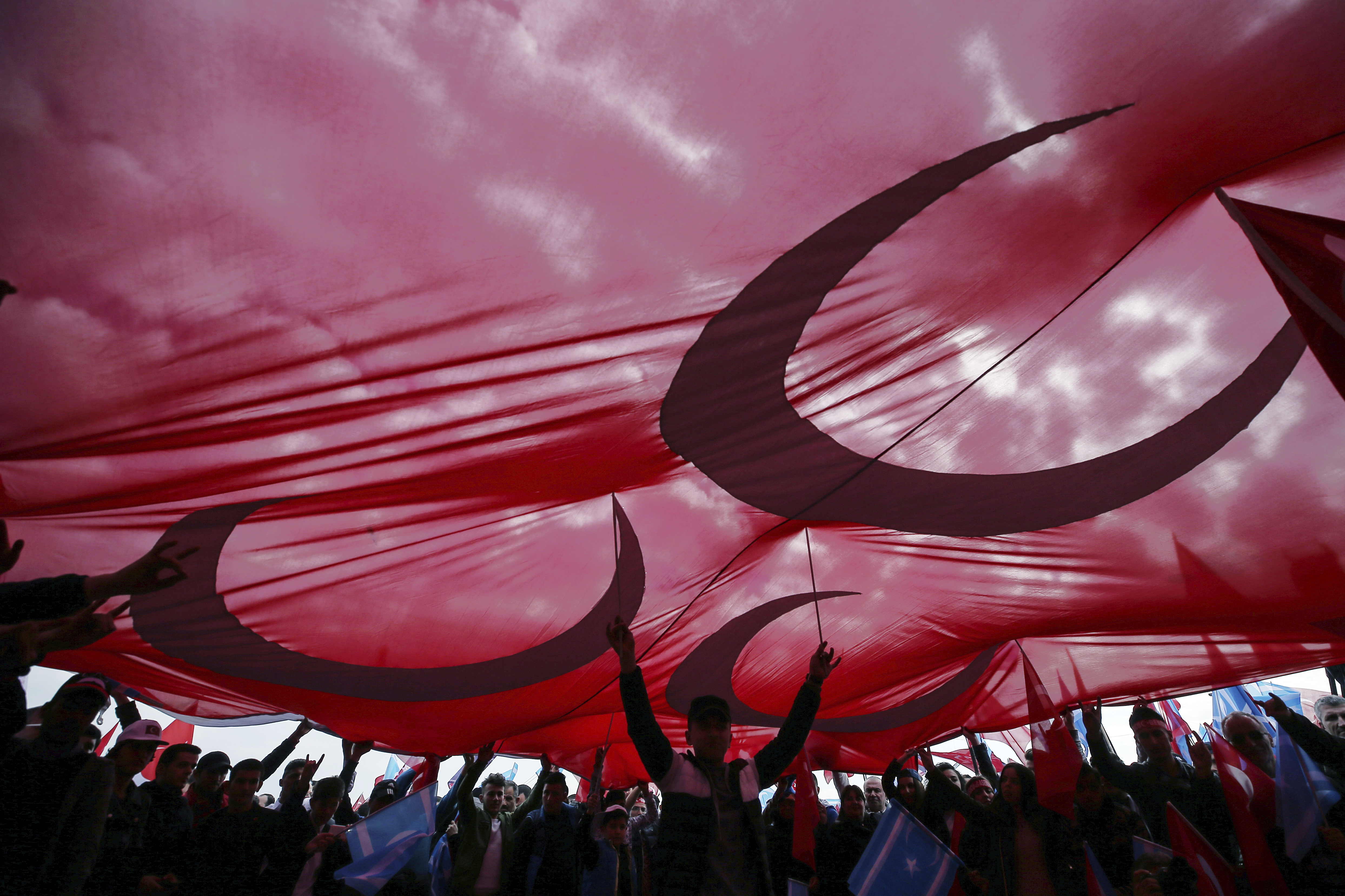 Supporters hold a huge flag as they listen to Devlet Bahceli, the leader of Turkey's opposition Nationalist Movement Party, who supports President Recep Tayyip Erdogan, during a referendum rally in Istanbul, Sunday, April 9, 2017. Turkey is heading to a contentious April 16 referendum on constitutional reforms to expand Erdogan's powers.(AP Photo/Emrah Gurel)