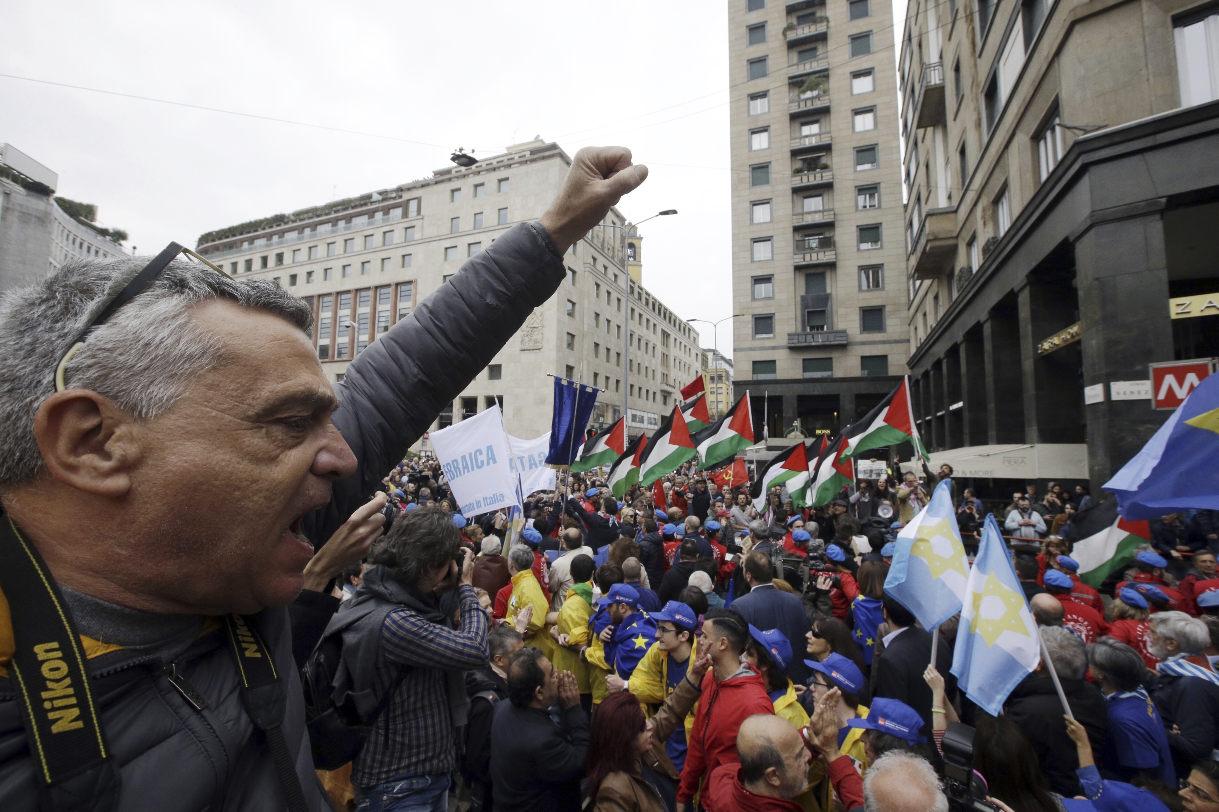 People hold up a flag of the Jewish Brigade as Palestinians flags wave in background during a demonstration to mark Italy's Liberation day, in Milan, Italy, Tuesday, April 25, 2017. Italy is celebrating the anniversary of a partisan uprising against the Nazis and their Fascist allies at the end of World War II. (AP Photo/Luca Bruno)