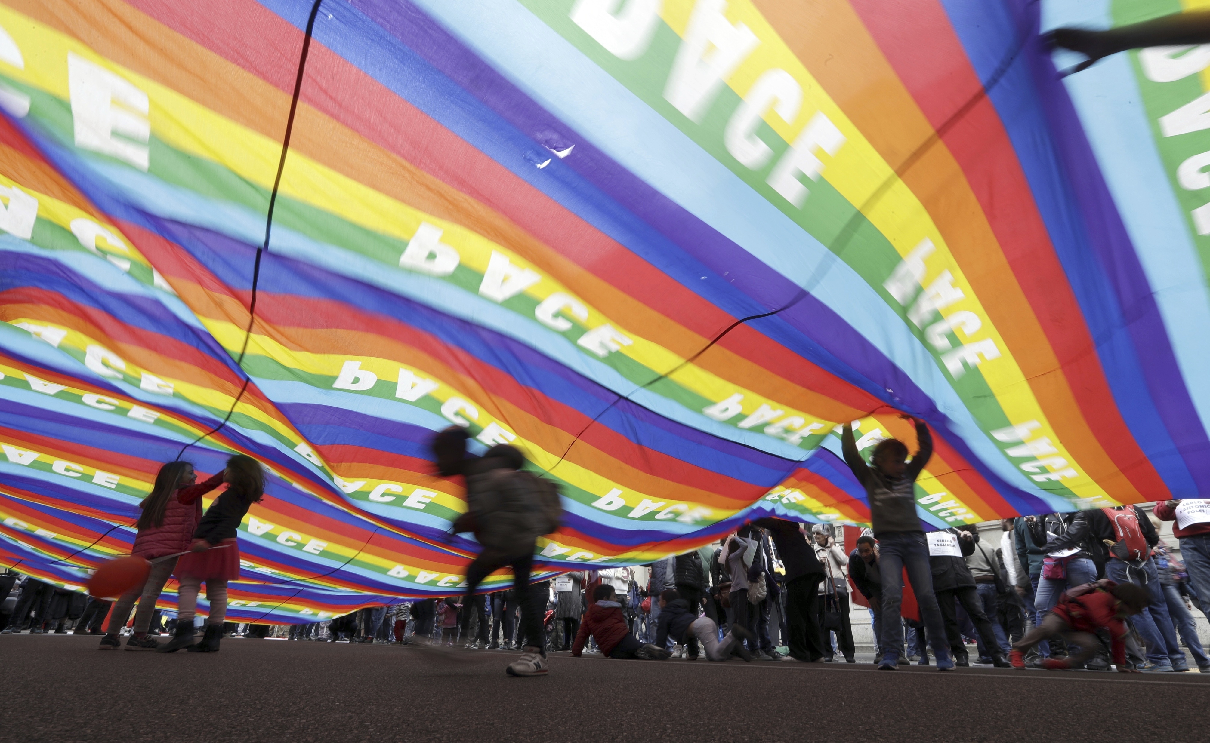 People unfold a giant rainbow flag reading peace as they march during a demonstration to mark Italy's Liberation day, in Milan, Italy, Tuesday, April 25, 2017. Italy is celebrating the anniversary of a partisan uprising against the Nazis and their Fascist allies at the end of World War II. (AP Photo/Luca Bruno)