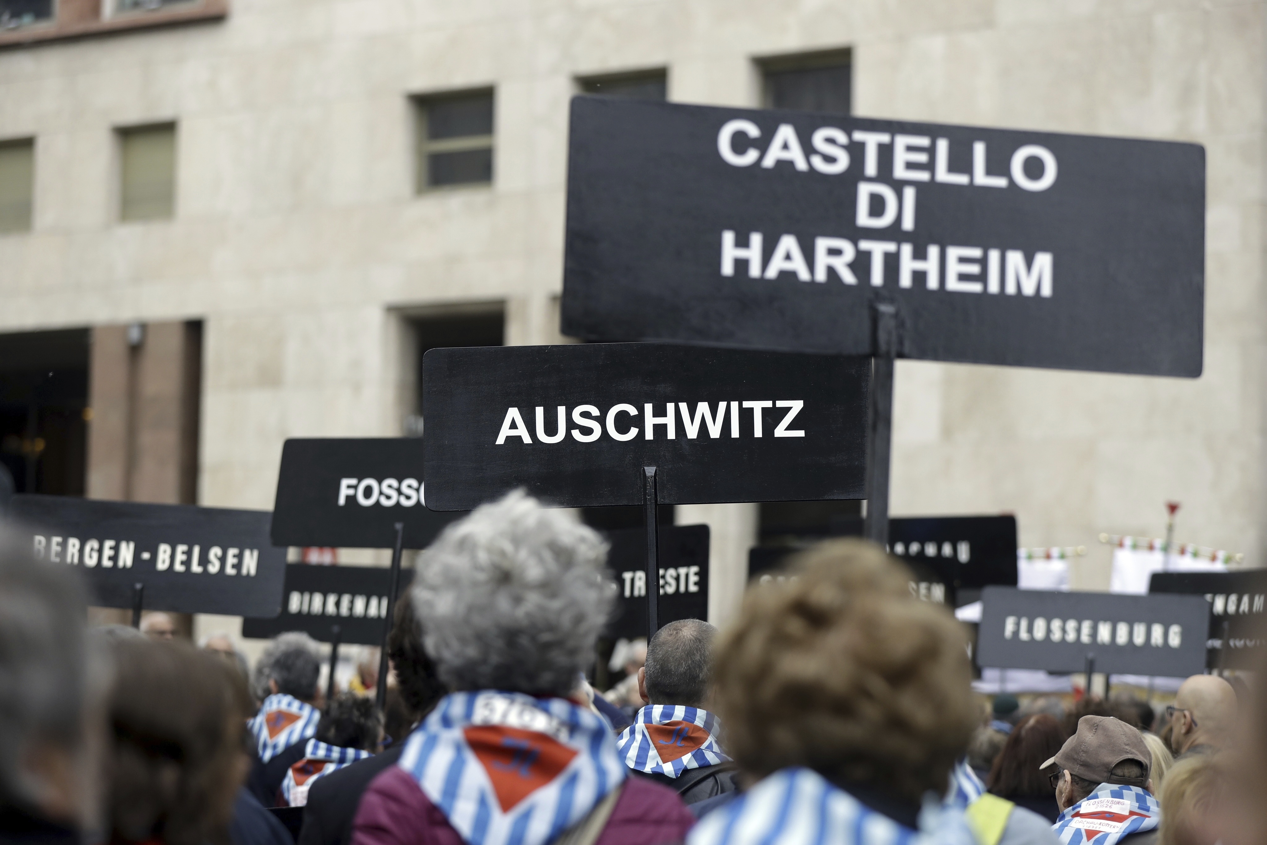 People hold signs reading the names of Nazi concentration camps during a demonstration to mark Italy's Liberation day, in Milan, Italy, Tuesday, April 25, 2017. Italy is celebrating the anniversary of a partisan uprising against the Nazis and their Fascist allies at the end of World War II. (AP Photo/Luca Bruno)