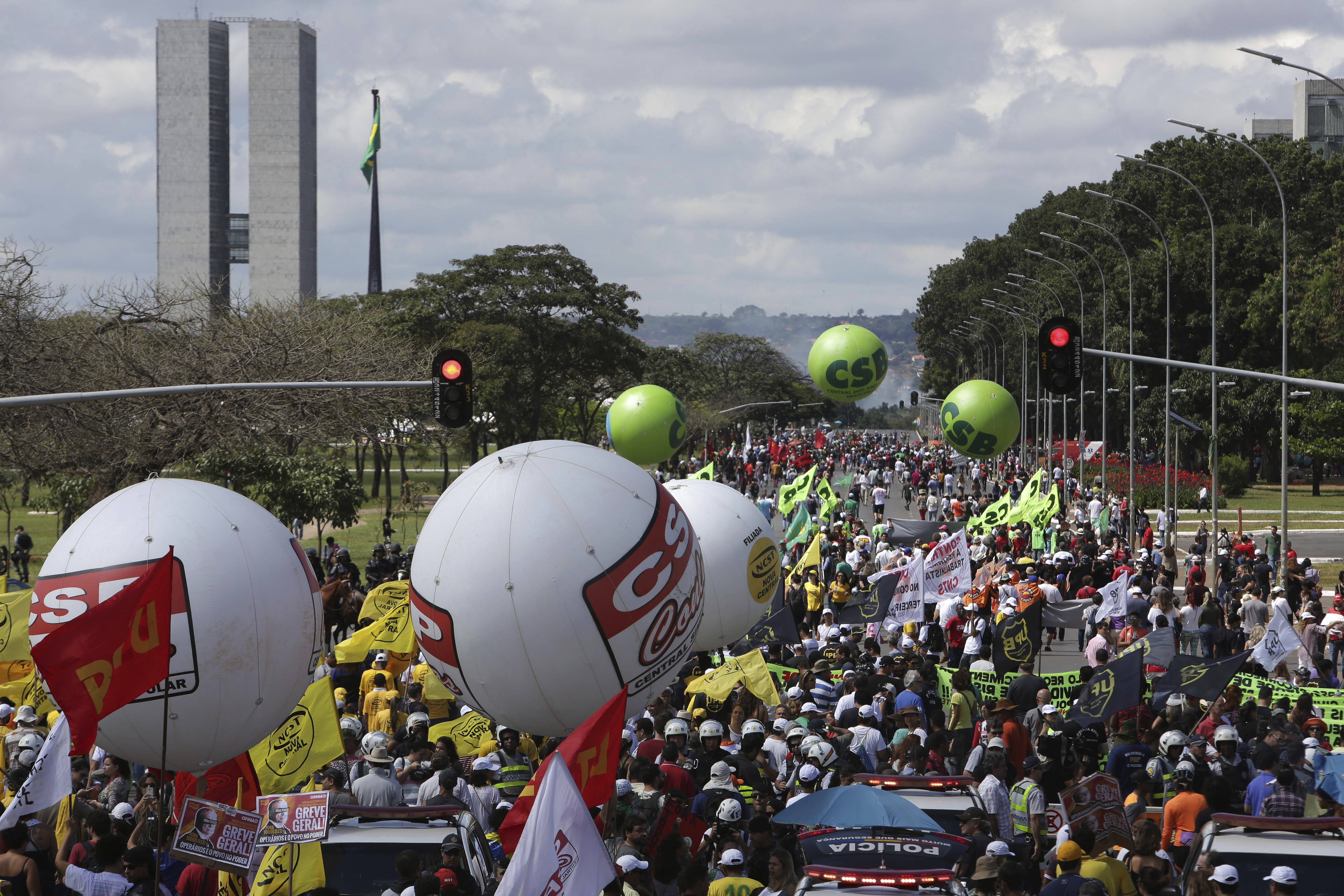 Demonstrators march during a general strike in Brasilia, Brazil, Friday, April 28, 2017. Public transport largely came to a halt across much of Brazil on Friday and protesters blocked roads and scuffled with police as part of a general strike to protest proposed changes to labor laws and the pension system. (AP Photo/Eraldo Peres)