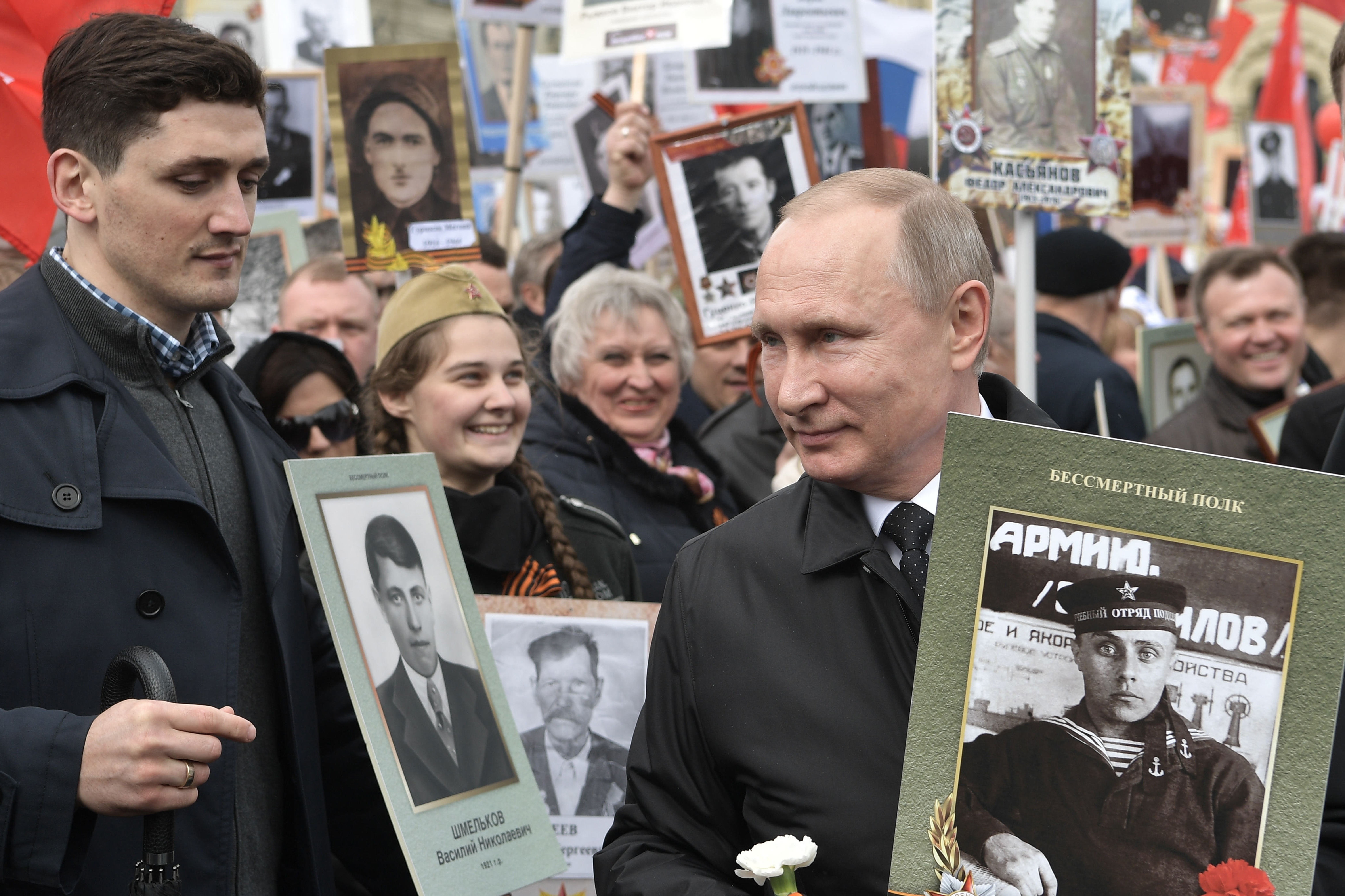 Russian President Vladimir Putin, right, holds a portrait of his father Vladimir Spiridonovich Putin as he walks among other people carrying portraits of relatives who fought in World War II, with Russian and Soviet flags, during the Immortal Regiment march at the Red Square in Moscow, Russia, on Tuesday, May 9, 2017, celebrating 72 years since the end of WWII and the defeat of Nazi Germany. (Alexei Nikolsky, Sputnik, Kremlin Pool Photo via AP)