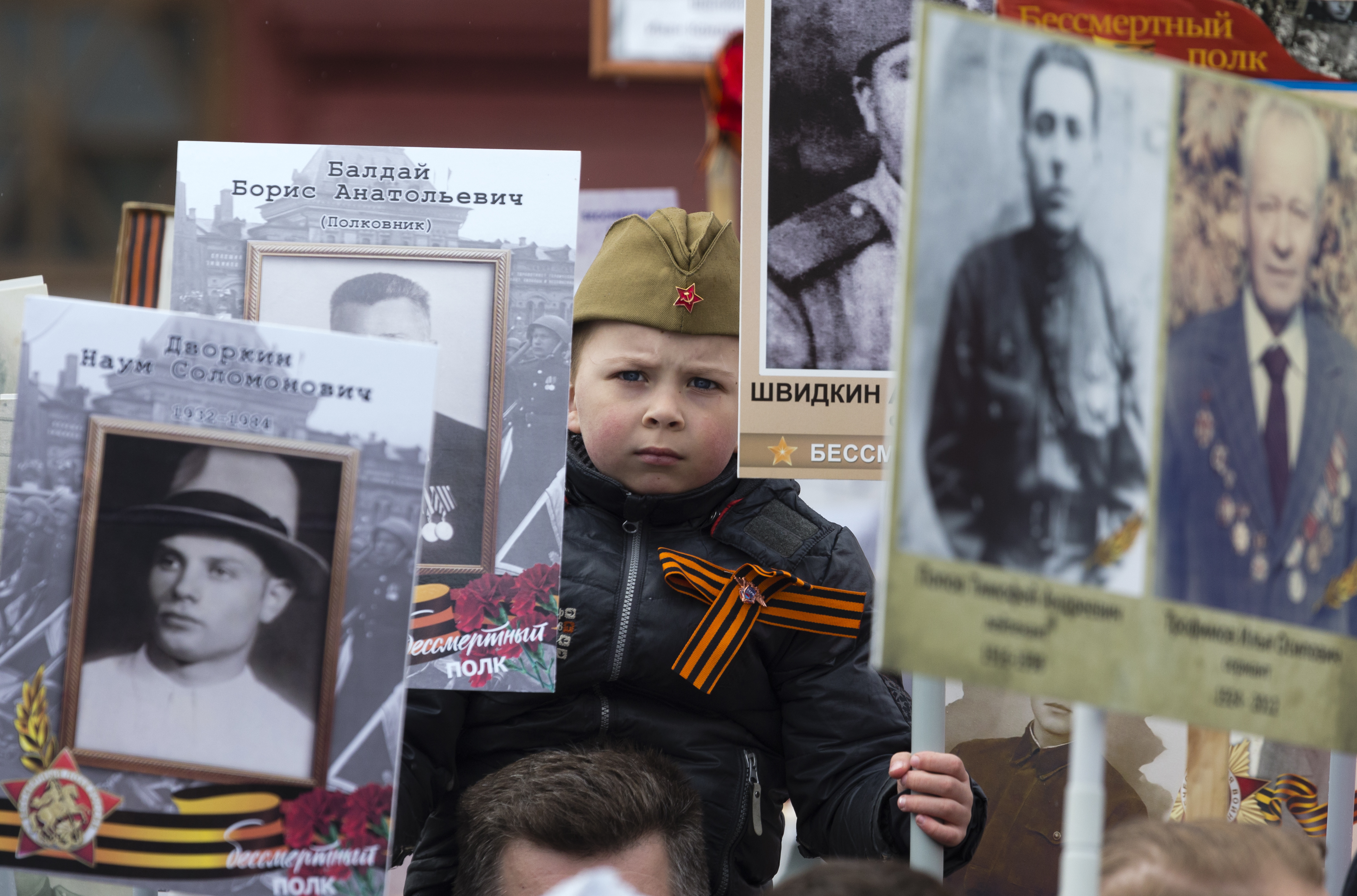 A Russian boy holds portraits of relatives who fought in World War II, Russian and Soviet flags, during the Immortal Regiment march at the Red Square in Moscow, Russia, Tuesday, May 9, 2017, celebrating 72 years since the end of WWII and the defeat of Nazi Germany. (AP Photo/Ivan Sekretarev)
