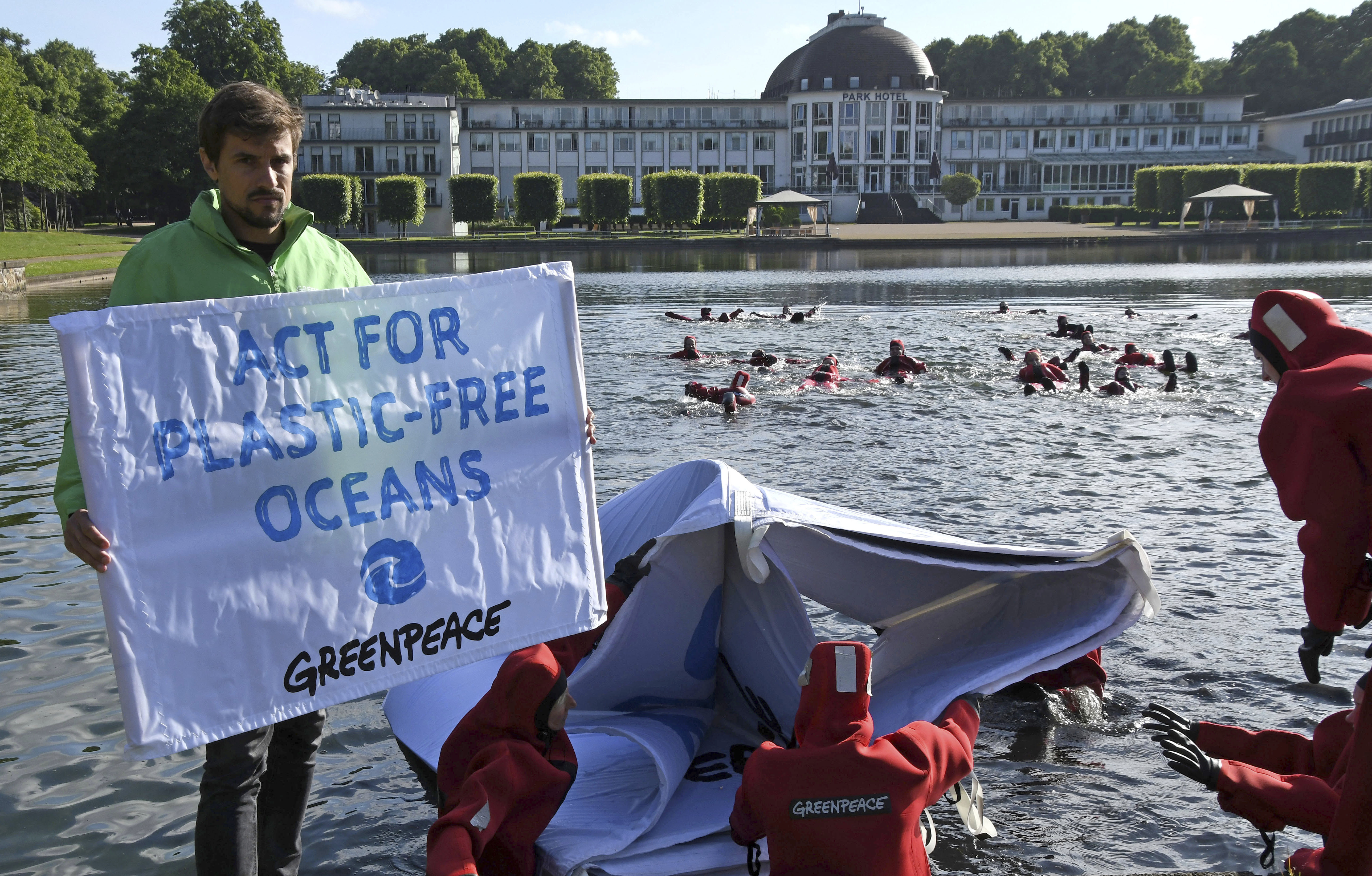 A'Greenpeace activist holding a banner as other activists get into Hollersee lake as part of the campaign 