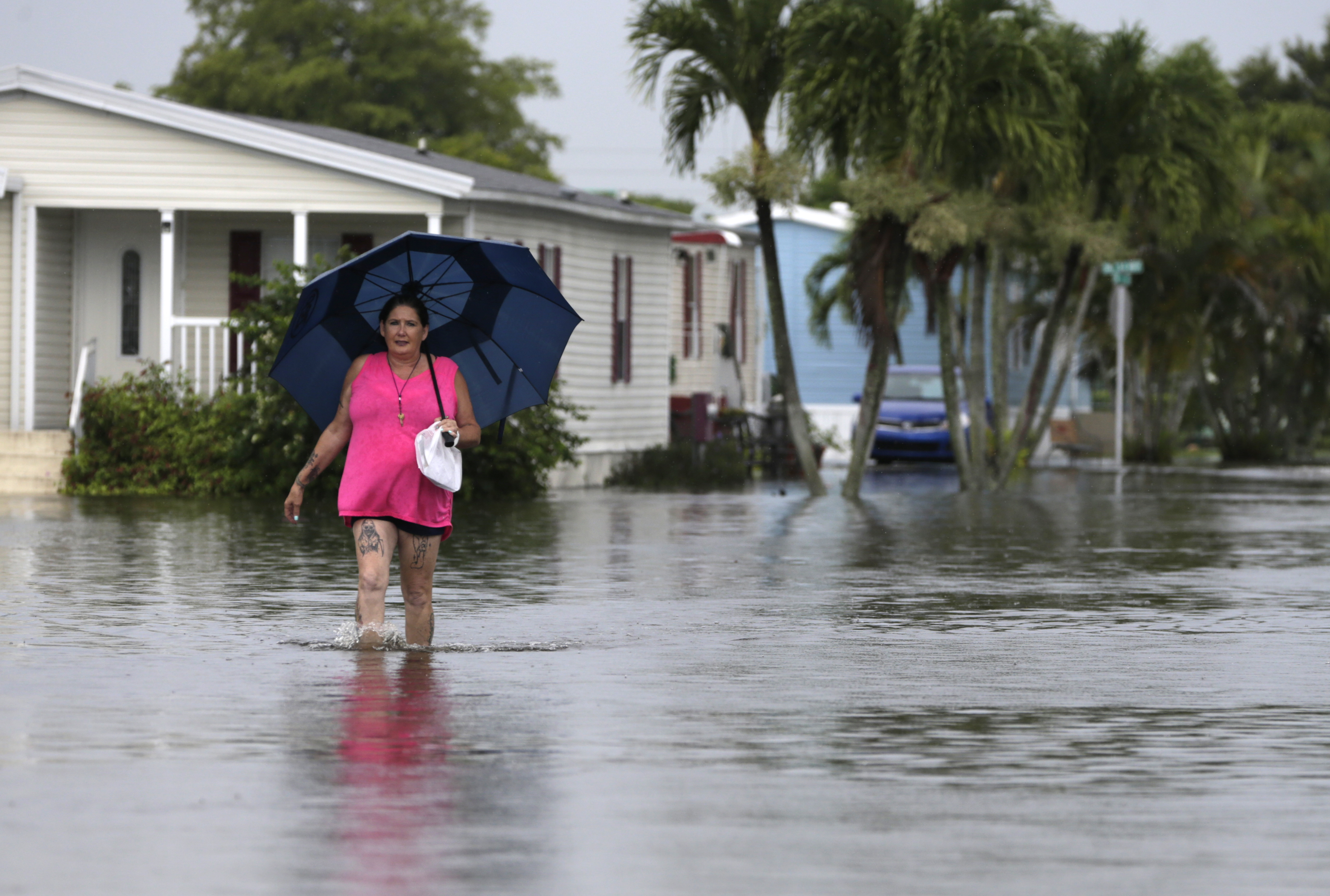 Peggy Wallace walks to her home in the Sunshine Village mobile home park, Wednesday, June 7, 2017, in Davie, Fla. Several South Florida cities set rainfall records as heavy rain continues to fall, bringing the potential for further flooding. (AP Photo/Lynne Sladky)