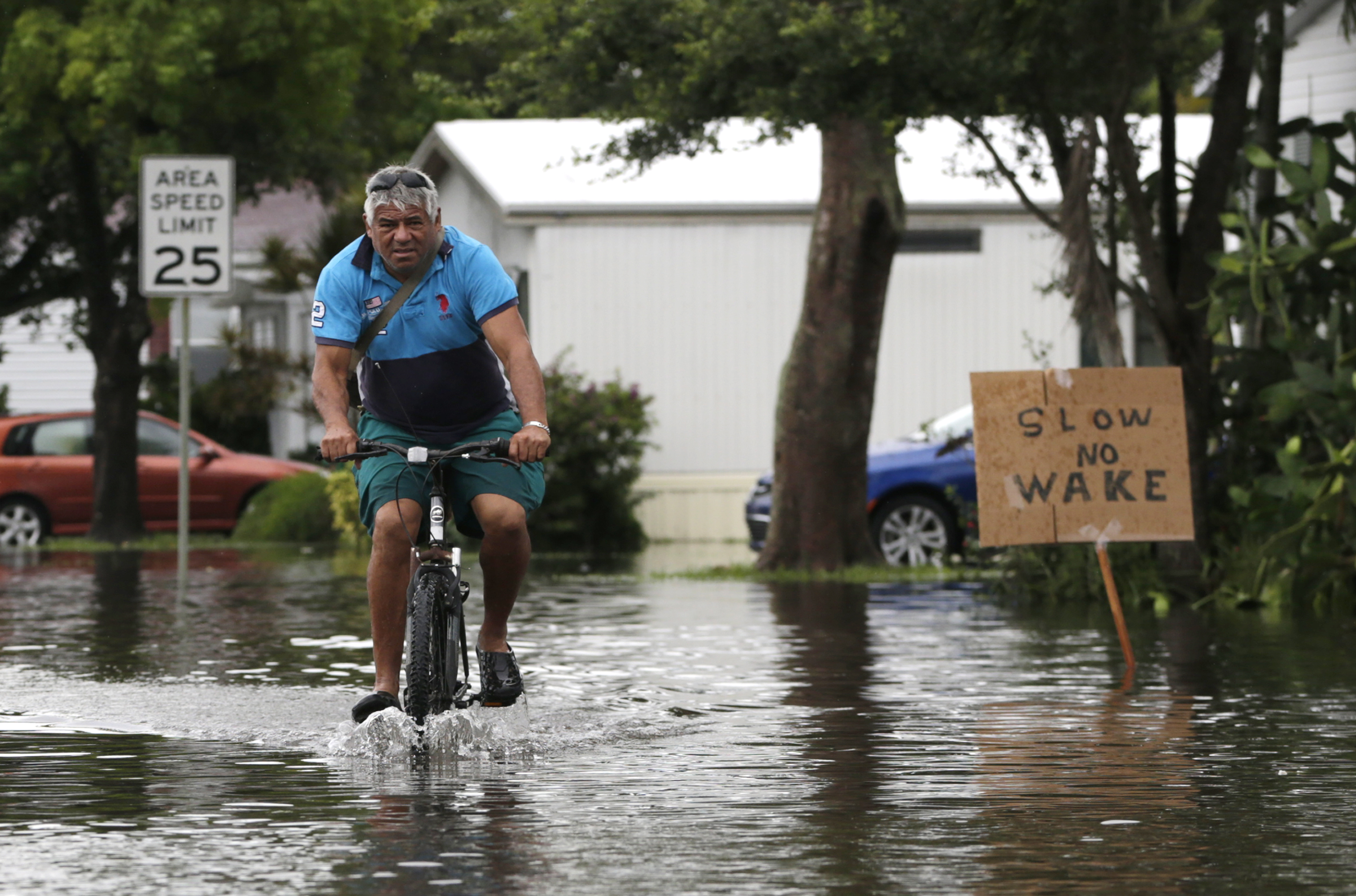 Dario Pavan rides his bicycle through flooded streets in the Sunshine Village mobile home park, Wednesday, June 7, 2017, in Davie, Fla. Several South Florida cities set rainfall records as heavy rain continues to fall, bringing the potential for further flooding. (AP Photo/Lynne Sladky)