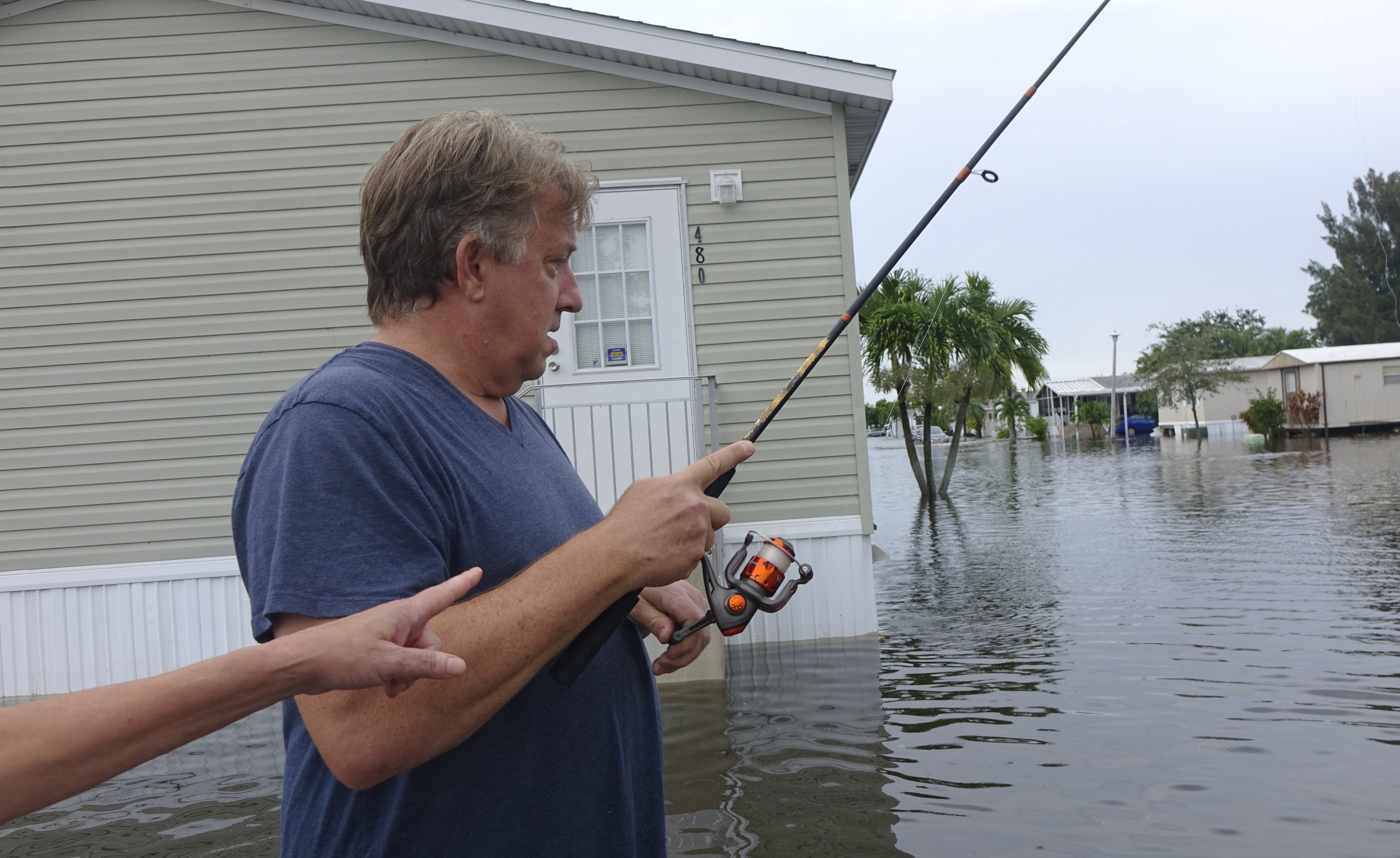 Mike Lemmerman tries his luck fishing on a flooded SW 5th St., in Sunshine Village, Wednesday, June 7, 2017, in Davie, Fla. Several days of constant rain has caused flooding throughout Broward and Palm Beach Counties. (Joe Cavaretta/South Florida Sun-Sentinel via AP)