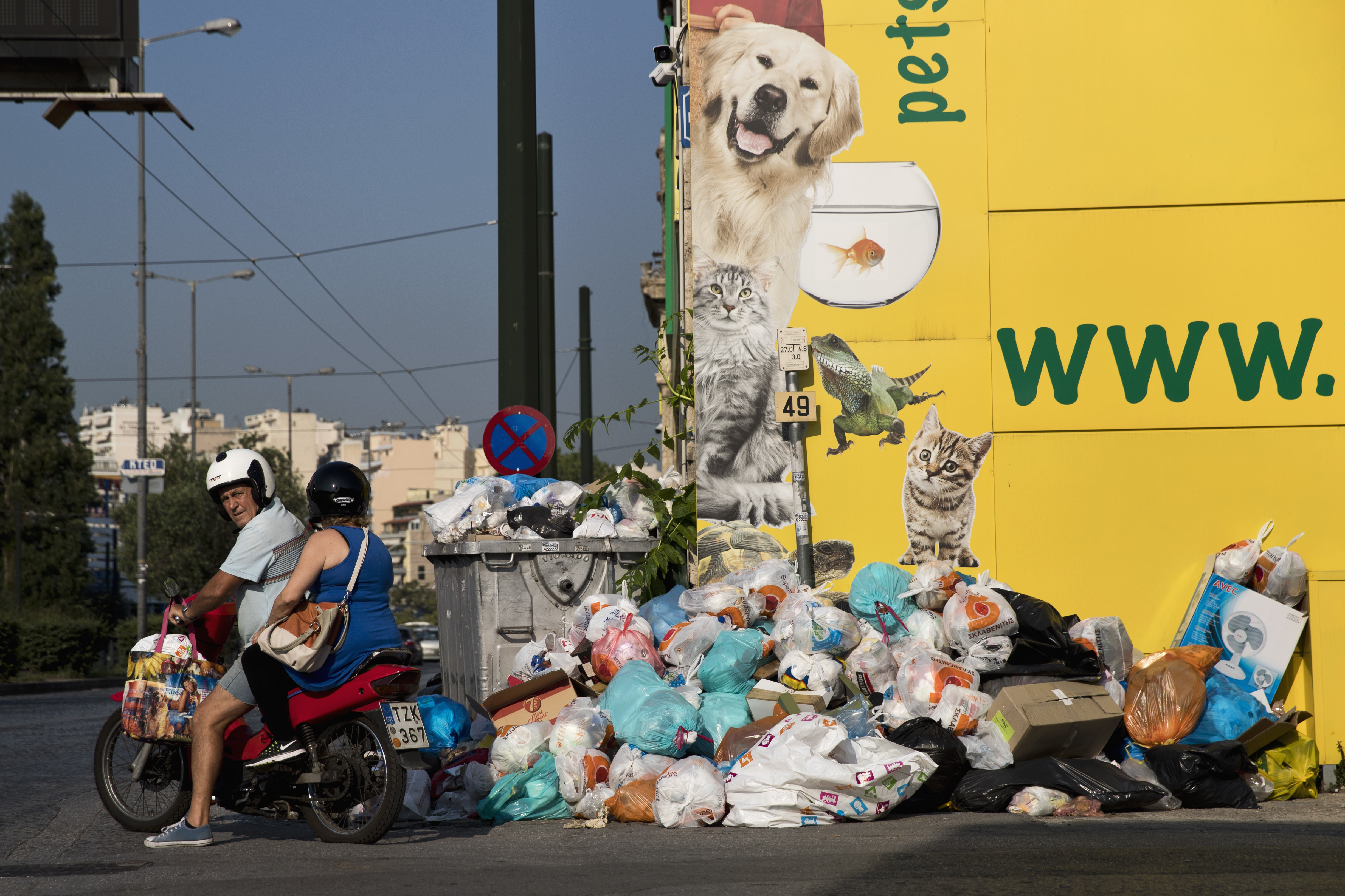 A motorcyclist looks on as he drives next to a pile of garbage in Piraeus, near Athens, on Monday, June 26, 2017. Municipality workers have been on strike for almost a week , hindering trash collection across the country. (AP Photo/Petros Giannakouris)