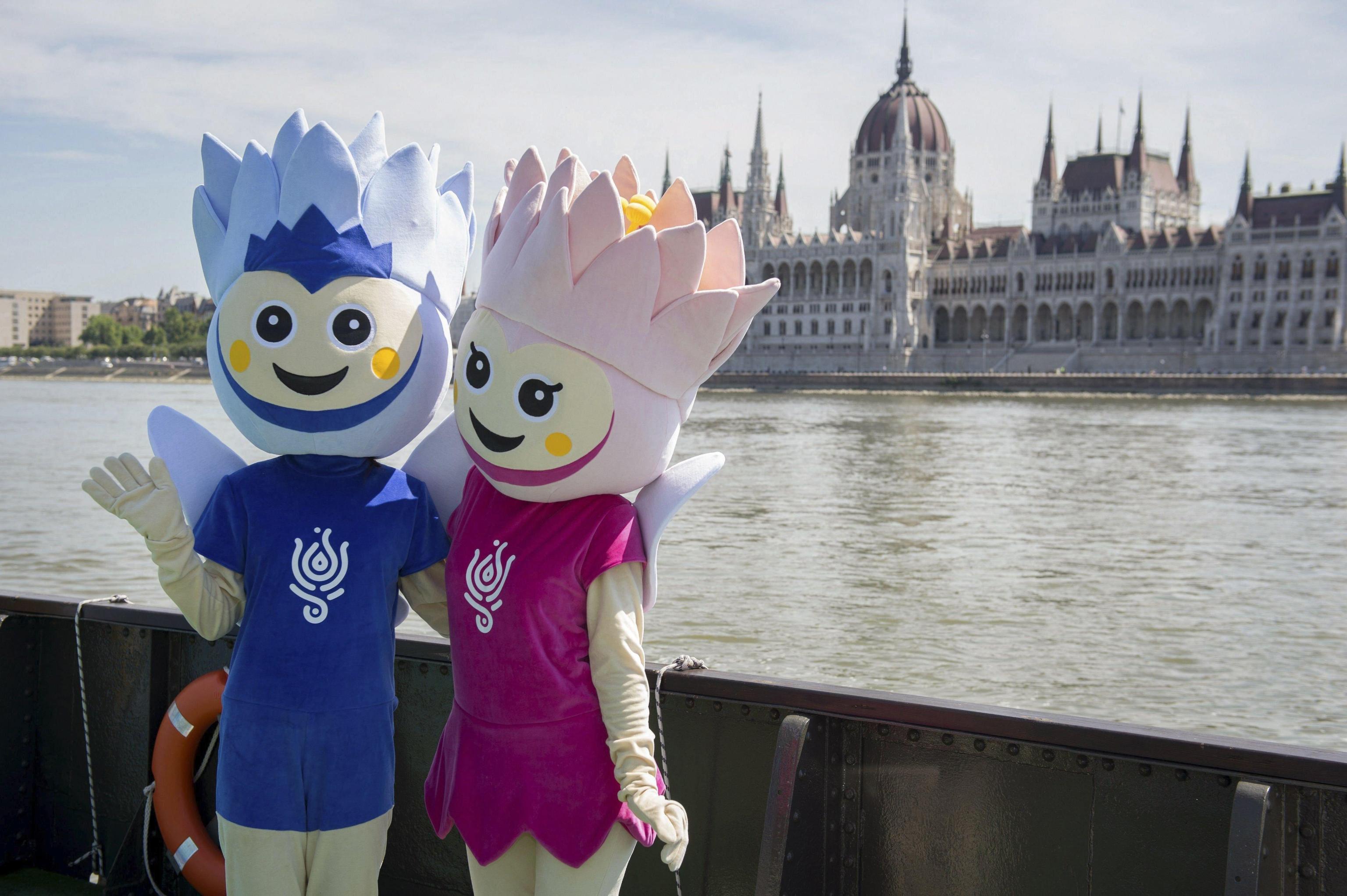 epa06085209 Lali and Lili, the two mascots of 2017 FINA World Aquatics Championships pose next to the visitors' centre at the lower embankment of Buda, in the background the building of the Hungarian Parliament is seen in Budapest, Hungary, 06 July 2017 (issued 13 July). The FINA World Aquatics Championships 2017 will be held in Hungary between July 14 and 30.  EPA/Csilla Cseke HUNGARY OUT