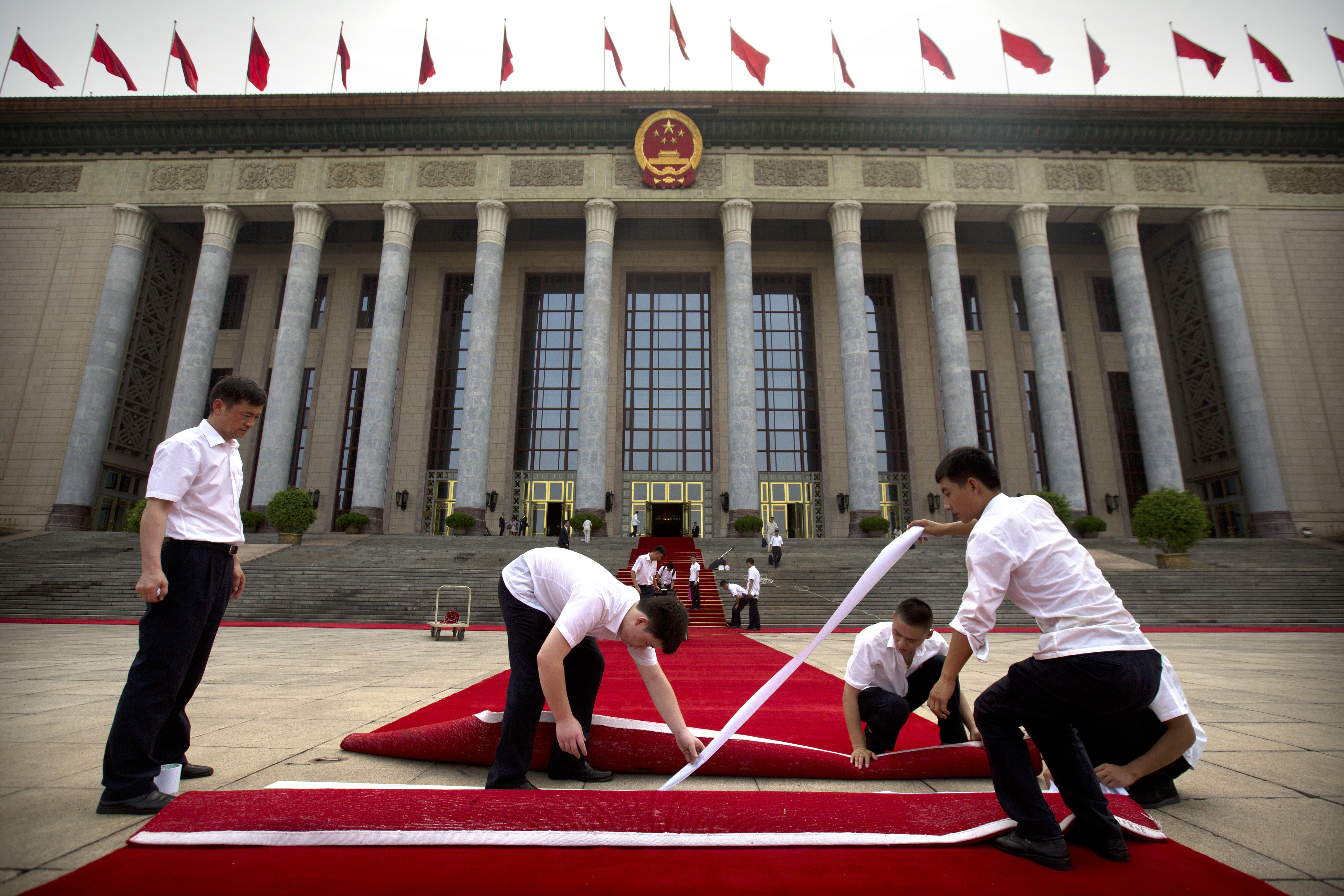 Workers use strips of adhesive tape as they lay down a red carpet in front of the Great Hall of the People before a welcome ceremony for Palestinian President Mahmoud Abbas in Beijing, Tuesday, July 18, 2017. (AP Photo/Mark Schiefelbein)