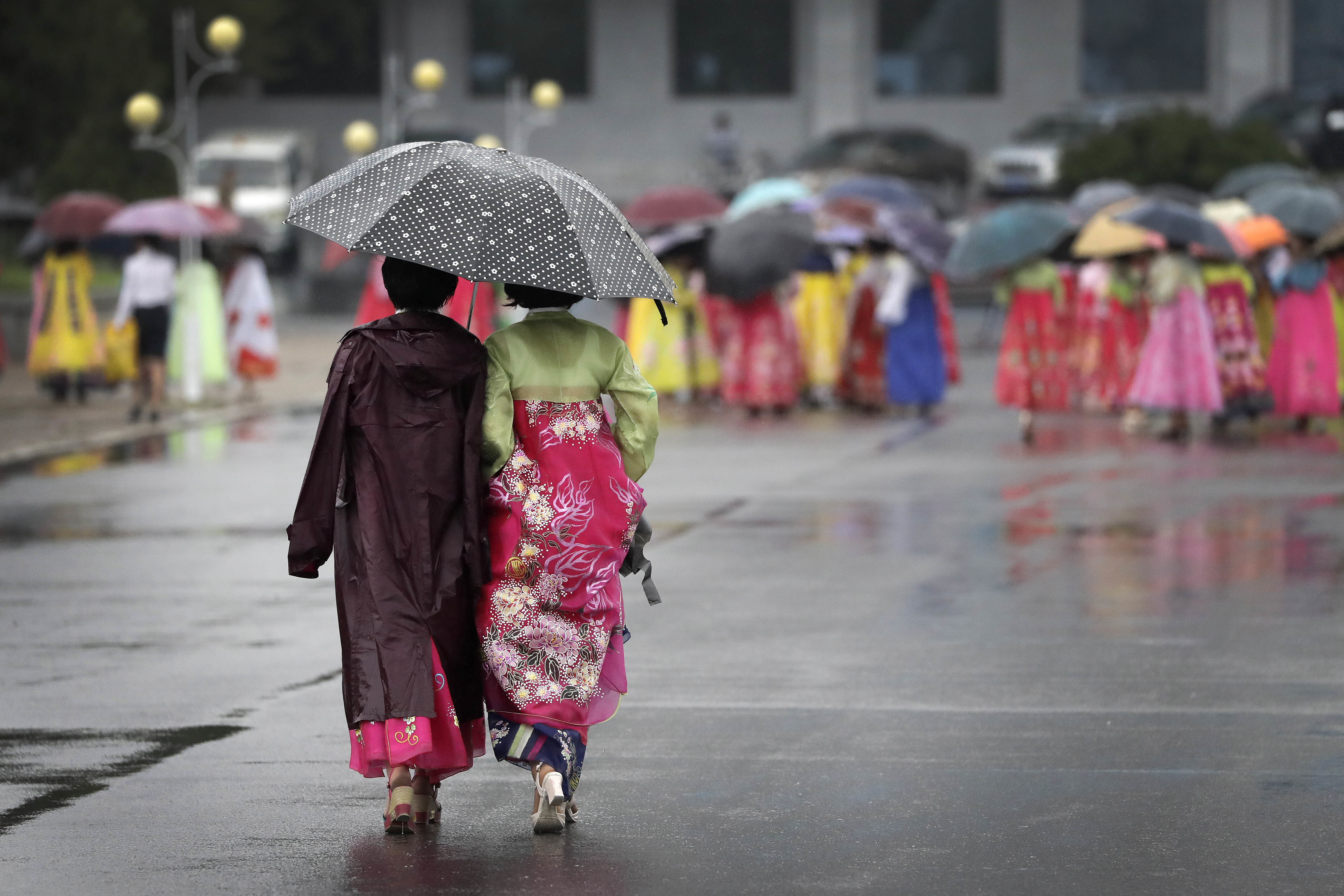 Two university students walk in the rain to a mass dance event on Thursday, July 27, 2017, in Pyongyang, North Korea as part of celebrations for the 64th anniversary of the armistice that ended the Korean War. (AP Photo/Wong Maye-E)
