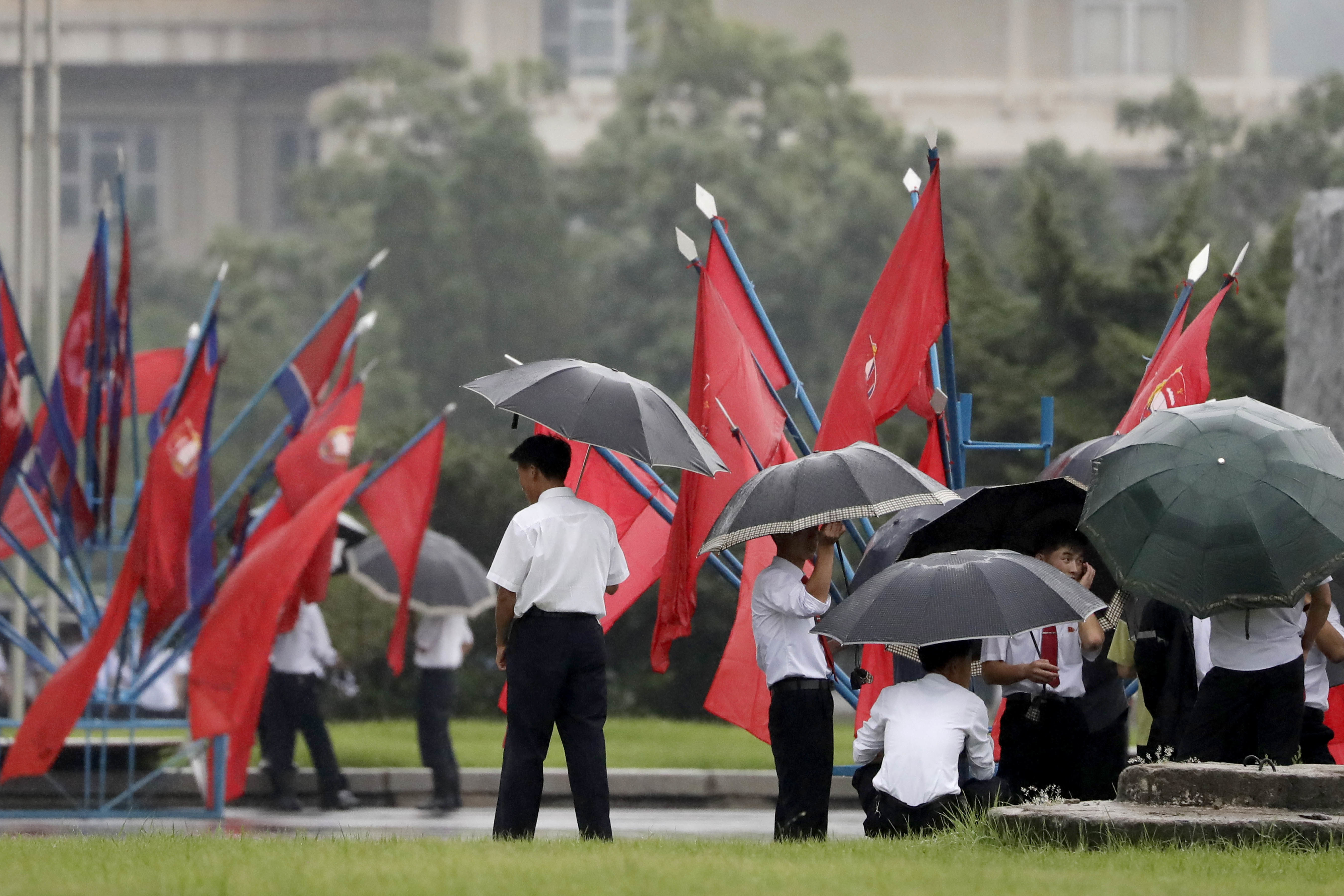 University students wait in the rain for the start of a mass dance event on Thursday, July 27, 2017, in Pyongyang, North Korea as part of celebrations for the 64th anniversary of the armistice that ended the Korean War. (AP Photo/Wong Maye-E)