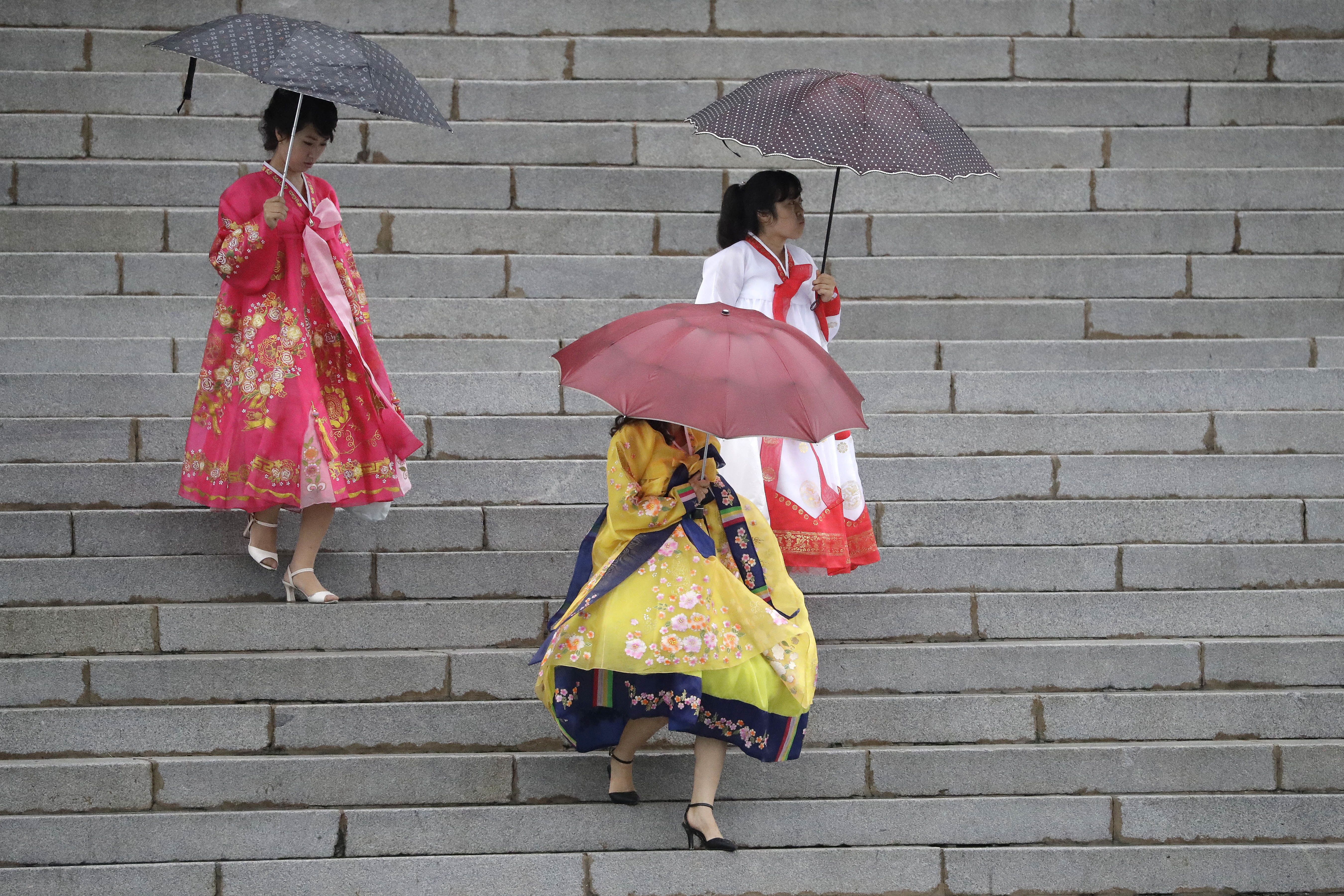 North Korean university students wearing their traditional Korean dresses make their way for a mass dance event in the rain on Thursday, July 27, 2017, in Pyongyang, North Korea as part of celebrations for the 64th anniversary of the armistice that ended the Korean War. (AP Photo/Wong Maye-E)