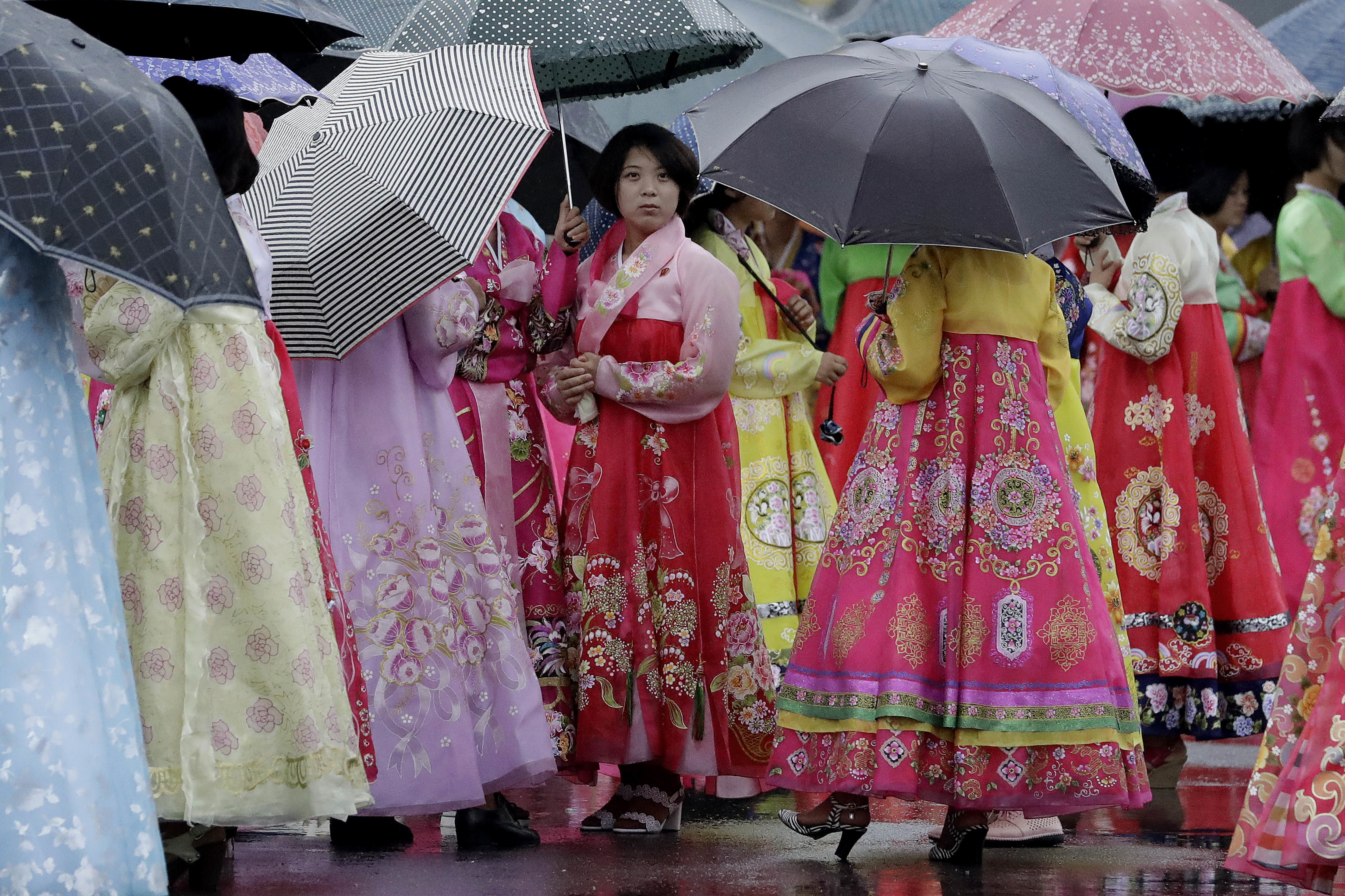 University students wearing traditional Korean dresses wait in the rain for the start of a mass dance on Thursday, July 27, 2017, in Pyongyang, North Korea as part of celebrations for the 64th anniversary of the armistice that ended the Korean War. (AP Photo/Wong Maye-E)