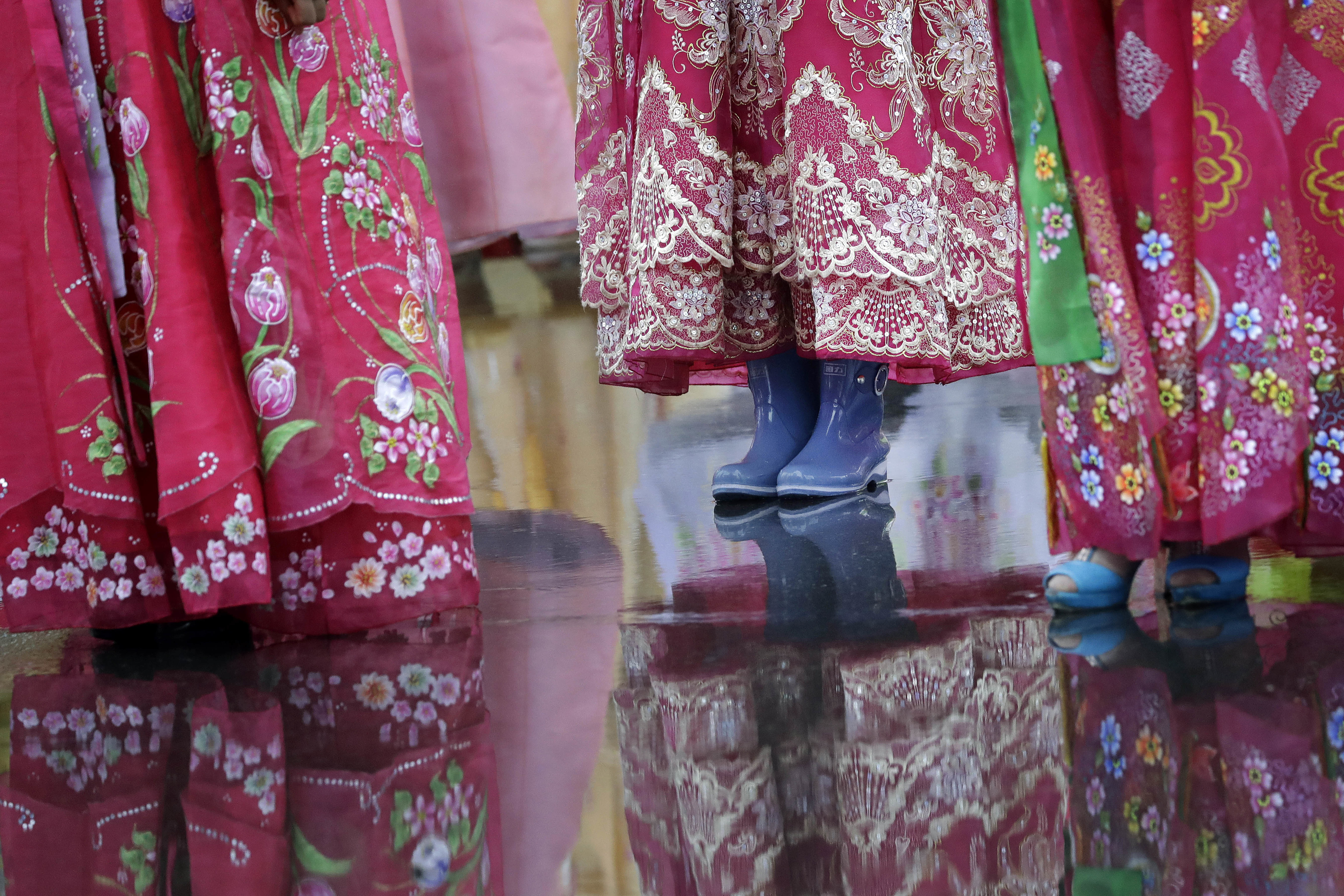 A university student wears a pair of rain boots with her traditional Korean dress as she waits in the rain for the start of a mass dance on Thursday, July 27, 2017, in Pyongyang, North Korea as part of celebrations for the 64th anniversary of the armistice that ended the Korean War. (AP Photo/Wong Maye-E)