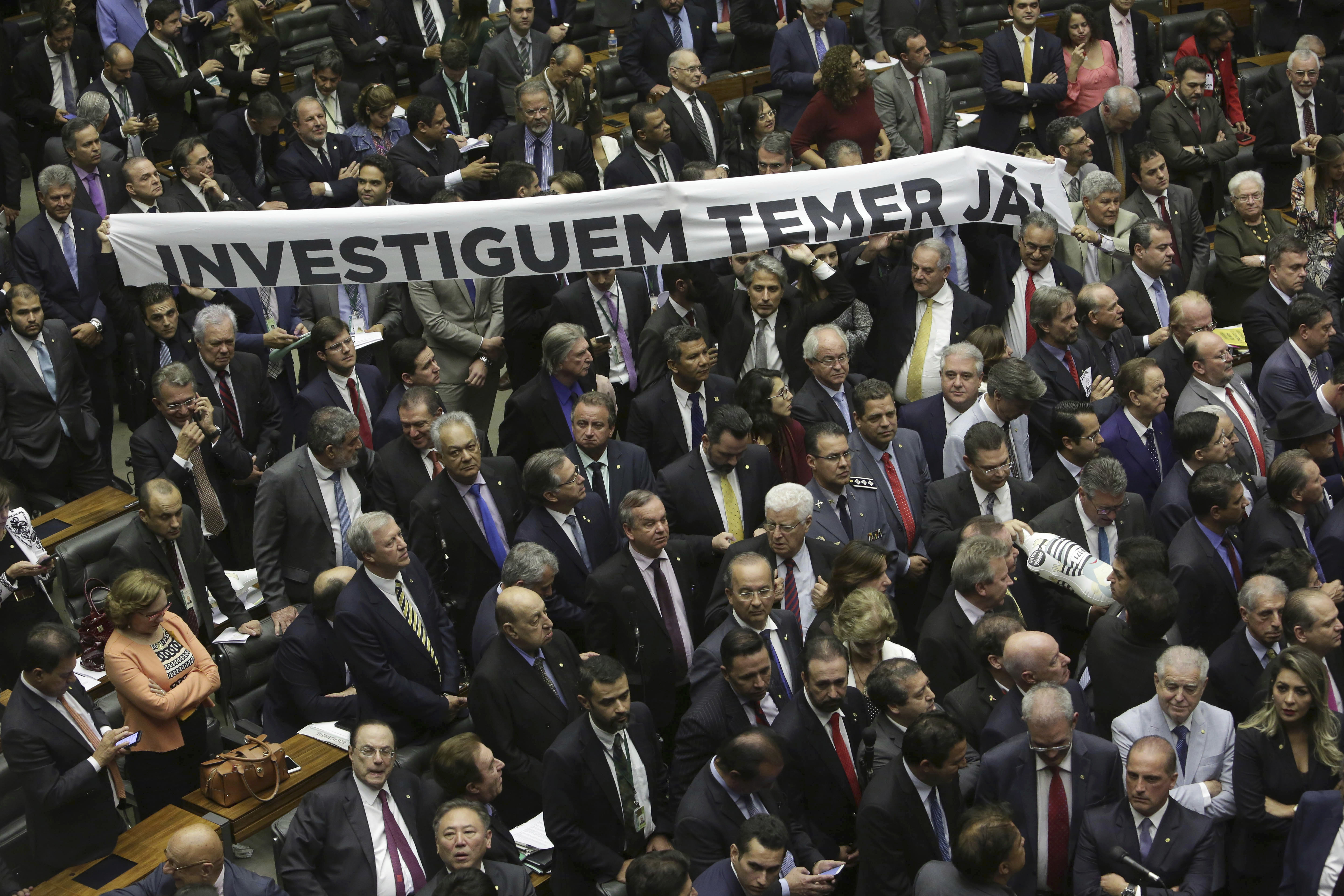 Opposition lawmakers hold a banner that reads in Portuguese: 