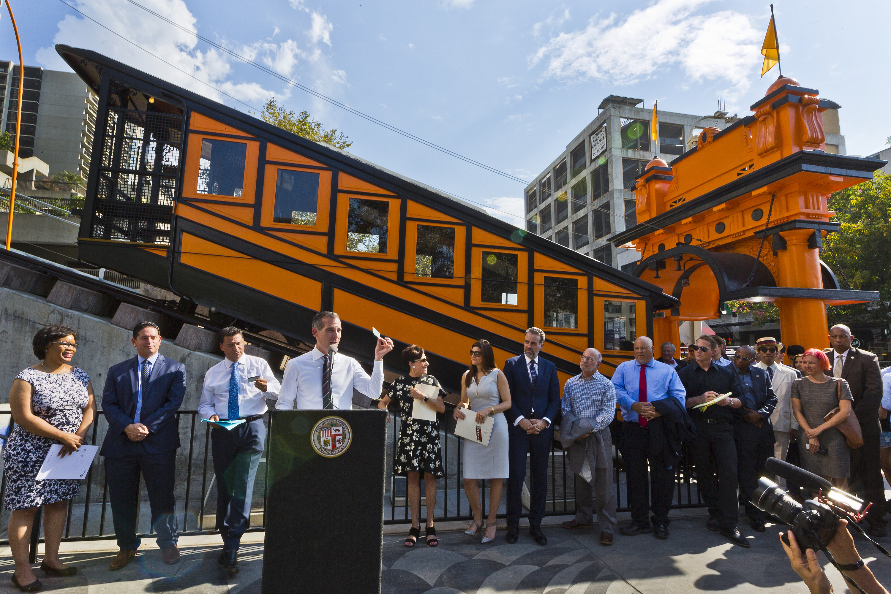 Los Angeles Mayor Eric Garcetti at podium, encourages riders to use their their Metro TAP cards before riding the Angels Flight Thursday, Aug. 31, 2017 in Los Angeles. Angels Flight, the beloved little railroad that's almost as much a symbol of Los Angeles as the Hollywood Sign, began pulling people toward the heavens and back down again Thursday after four years of idleness triggered by a 2013 derailment. (AP Photo/Damian Dovarganes)