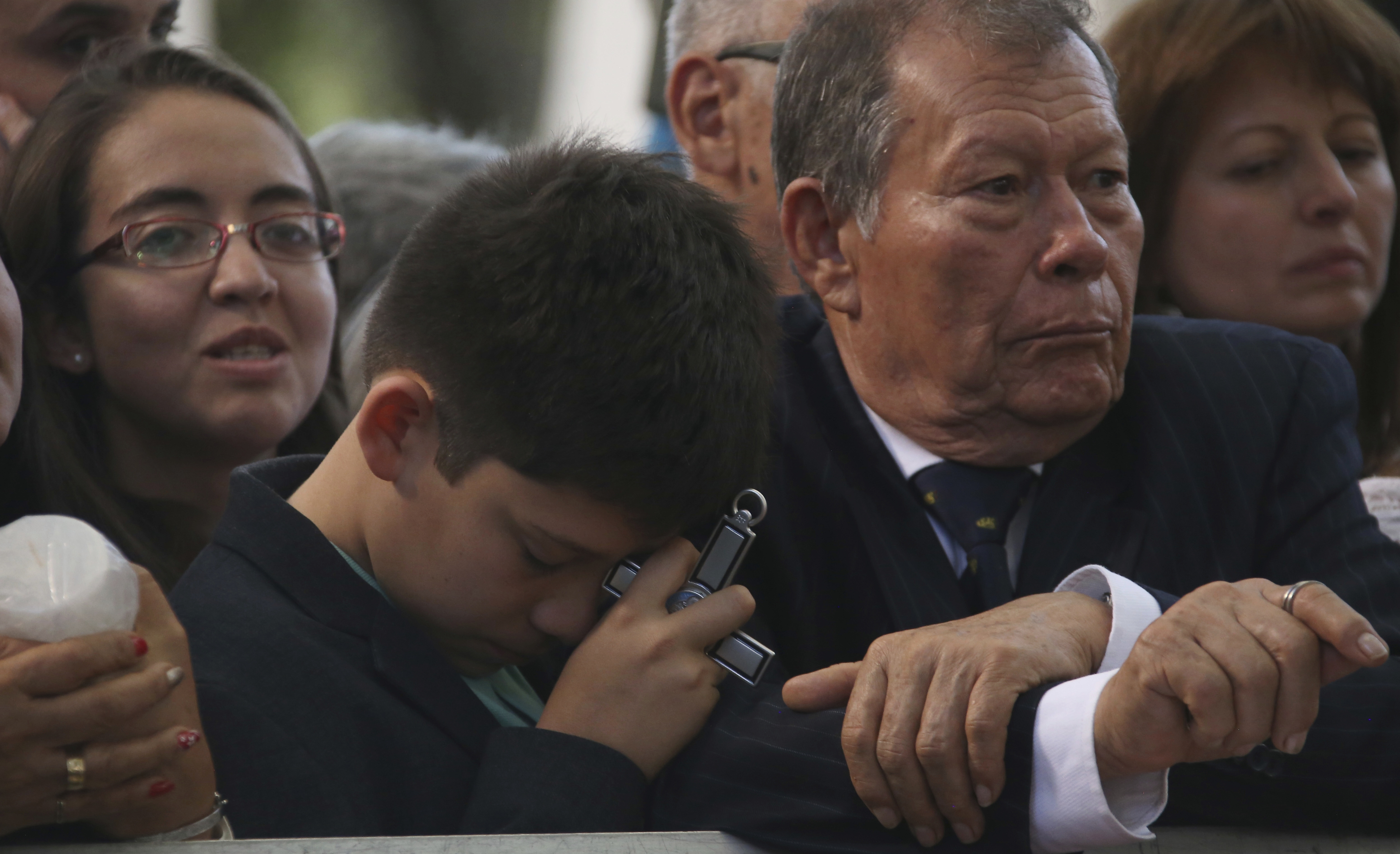 A boy prays holding a crucifix as he and others wait for Pope Francis at the nunciature in Bogota, Colombia, Wednesday, Sept. 6, 2017. (AP Photo/Ivan Valencia)