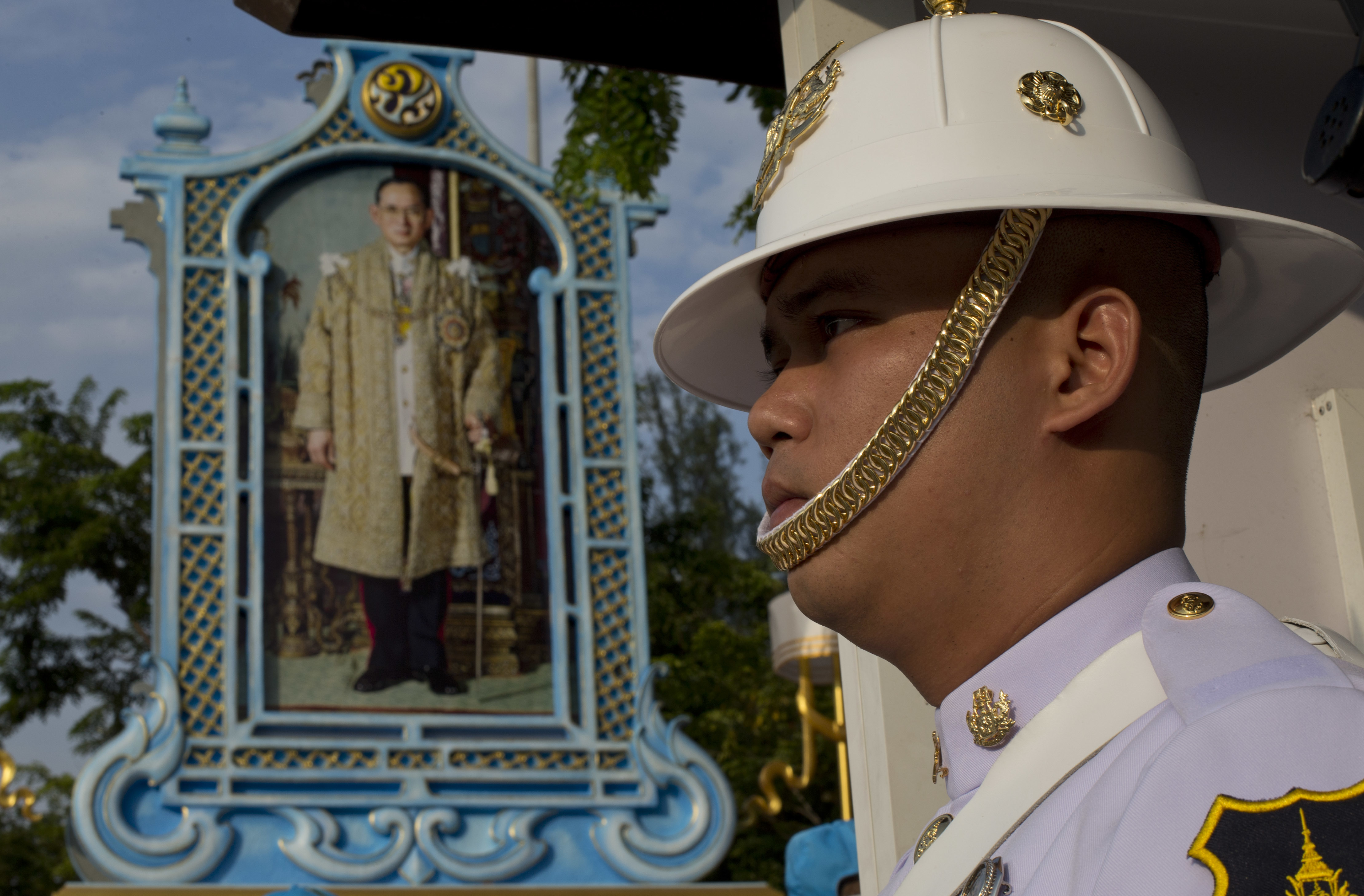A Thai honor guard member stands in front of a portrait of late Thai King Bhumibol Adulyadej  in Bangkok, Thailand, Wednesday, Oct. 25, 2017. Thailand on Wednesday began an elaborate five-day funeral for King Bhumibol Adulyadej with his son, the new monarch, performing Buddhist merit-making rites in preparation for moving Bhumibol's remains to a spectacular golden crematorium. (AP Photo/Gemunu Amarasinghe)