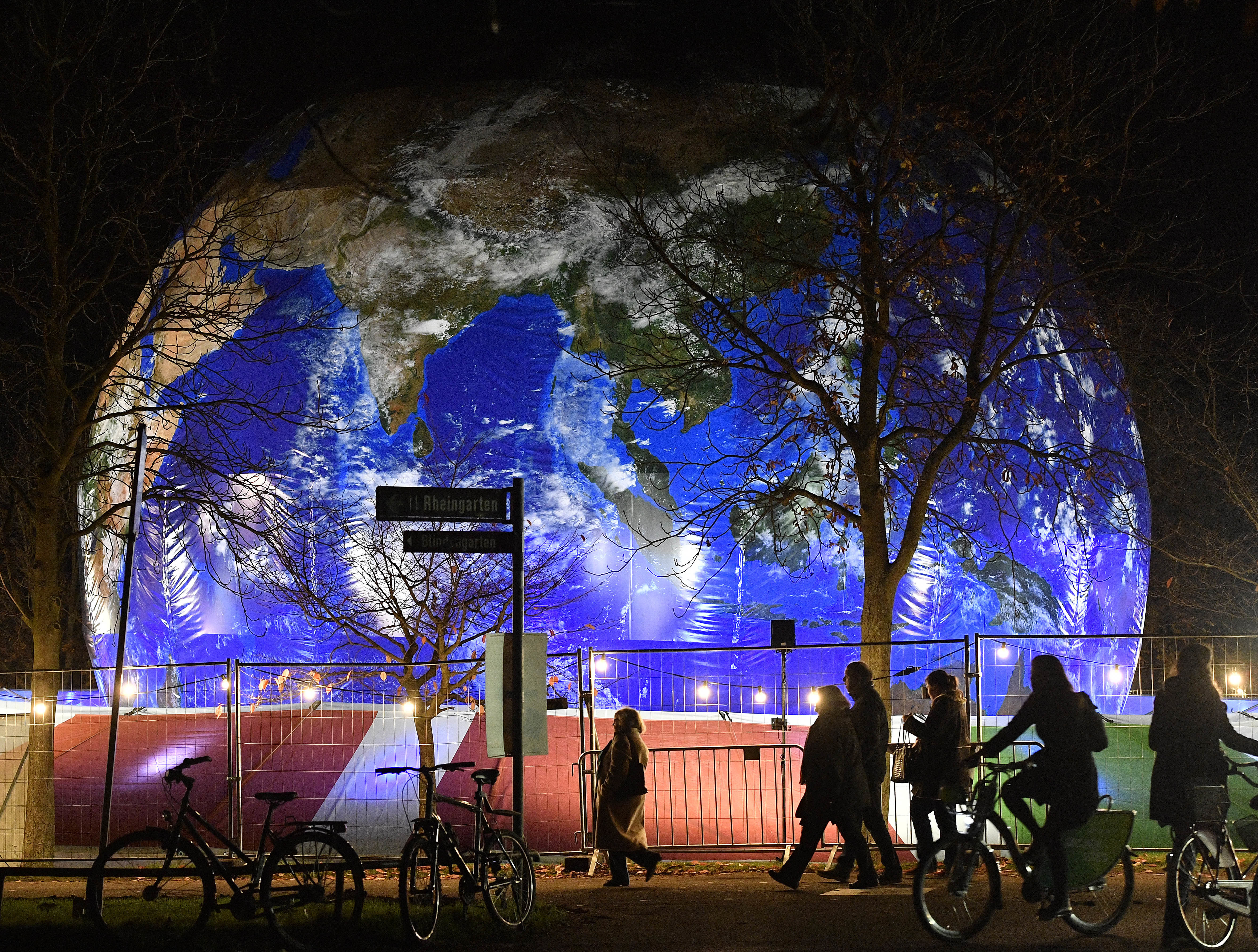 People pass the German pavilion in the shape of the earth during the COP 23 Fiji UN Climate Change Conference in Bonn, Germany, Wednesday evening, Nov. 15, 2017. (AP Photo/Martin Meissner)