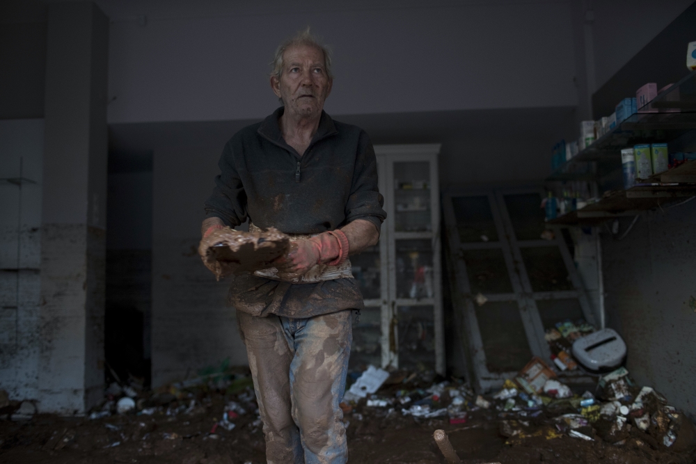 A man cleans mud from a destroyed pharmecy in the town of Mandra  western Athens, on Friday , Nov. 17, 2017. Hopes were diminishing as darkness fell Friday for six people reported missing in deadly flash floods that struck near Athens, killing 16.The fire department said search and rescue efforts continued to locate the six, all reported missing in the Mandra district which was the area hardest hit.(AP Photo/Petros Giannakouris)