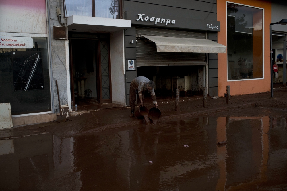 A man drops buckets with mud outside his house in the town of Mandra  western Athens, on Friday , Nov. 17, 2017. Hopes were diminishing as darkness fell Friday for six people reported missing in deadly flash floods that struck near Athens, killing 16.The fire department said search and rescue efforts continued to locate the six, all reported missing in the Mandra district which was the area hardest hit.(AP Photo/Petros Giannakouris)