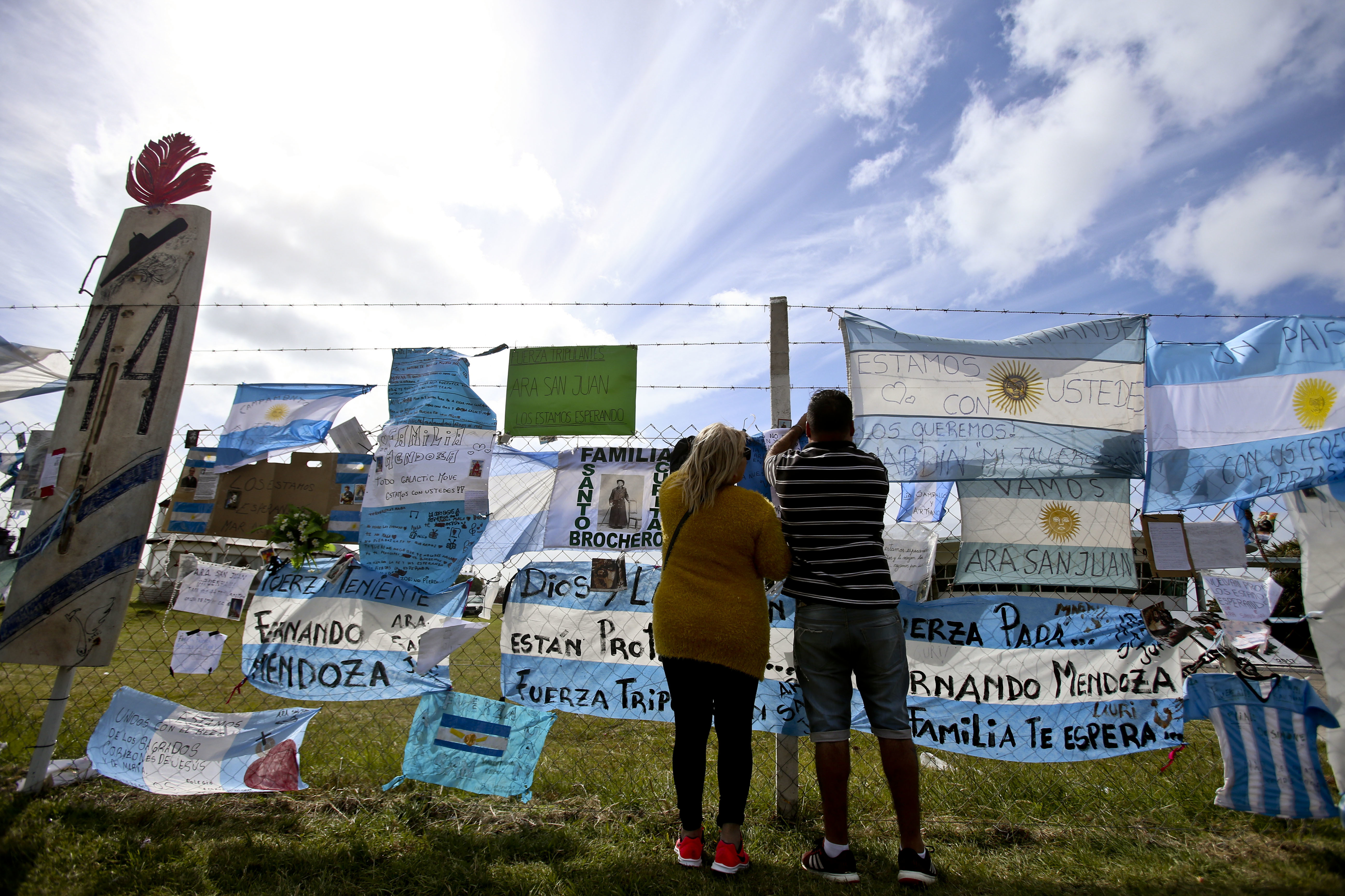 Friends and family of missing submarine crew members place a flag on the fence of the naval base in Mar de Plata, Argentina, Friday, Nov. 24, 2017. The Argentine navy says an explosion occurred near the time and place where the ARA San Juan submarine went missing on Nov. 15, leading some family members of the crew to give up hope of a rescue. (AP Photo/Esteban Felix)