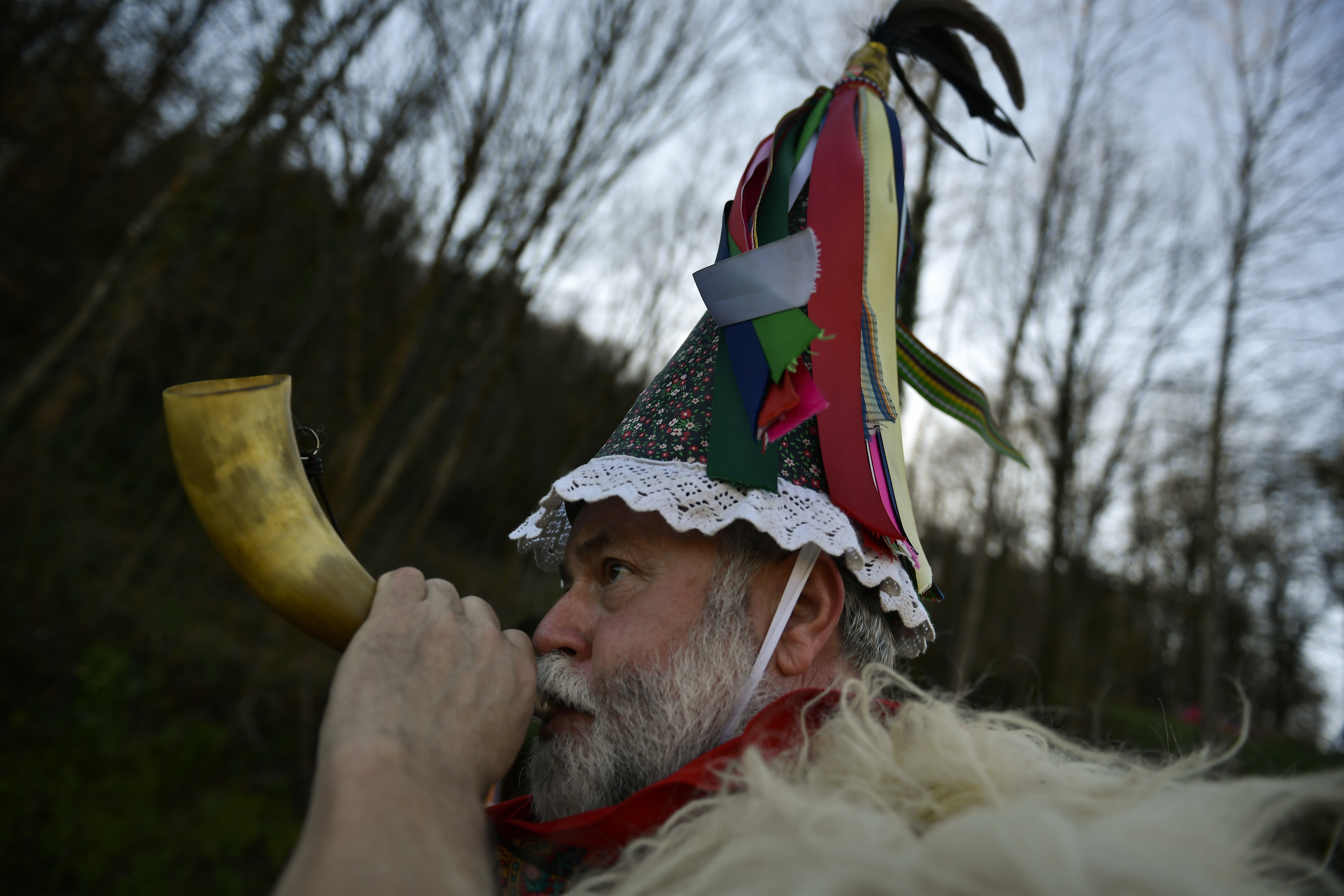A Joaldunak called Zanpantzar, plays a horn taking part in the Carnival between the Pyrenees villages of Ituren and Zubieta, northern Spain, Monday, Jan. 29, 2018. In one of the most ancient carnivals in Europe, dating from before the Roman empire, companies of Joaldunak (cowbells) made up of residents of two towns, Ituren and Zubieta, parade the streets costumed in sandals, lace petticoats, sheepskins around the waist and shoulders, coloured neckerchiefs, conical caps with ribbons and a hyssop of horsehair in their right hands and cowbells hung across their lower back. (AP Photo/Alvaro Barrientos)