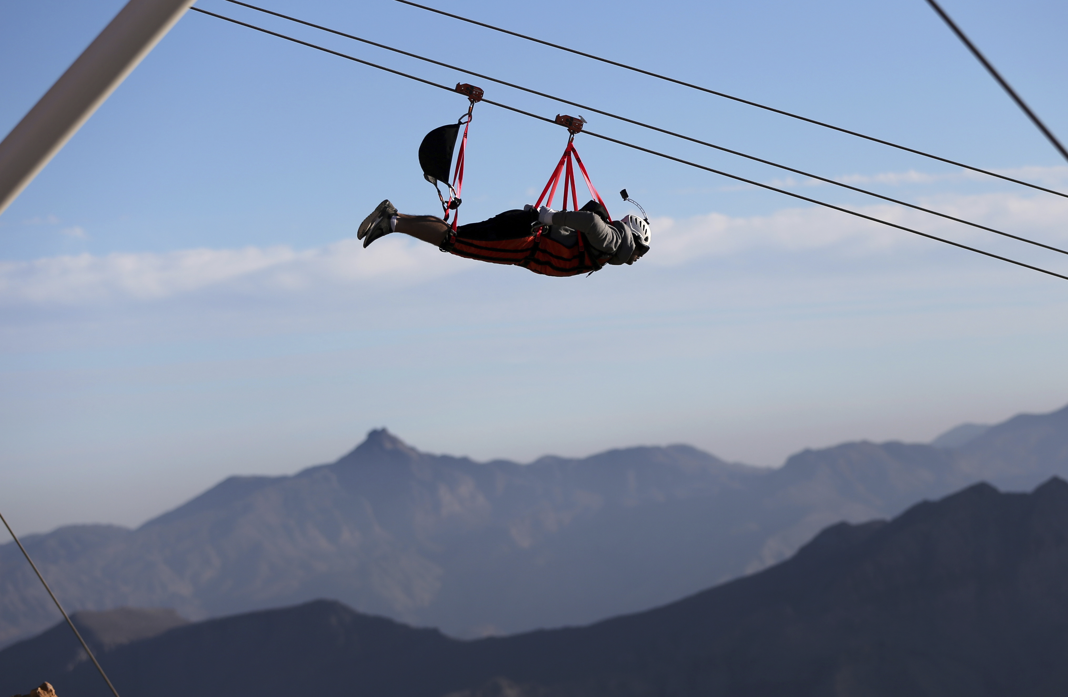 In this Wednesday, Jan. 31, 2018 photo,  a thrill-seeker rides from the UAE's highest mountain as he tries out a new zip line, on the peak of Jebel Jais mountain, 25 kms (15.5 miles) north east of Ras al-Khaimah, United Arab Emirates. The UAE is claiming a new world record with the opening of the world's longest zip line, measuring 2.83 kilometers (1.76 miles) in length. Guinness World Records officials certified the zip line on Thursday, the same day the attraction opened to the public. (AP Photo/Kamran Jebreili)