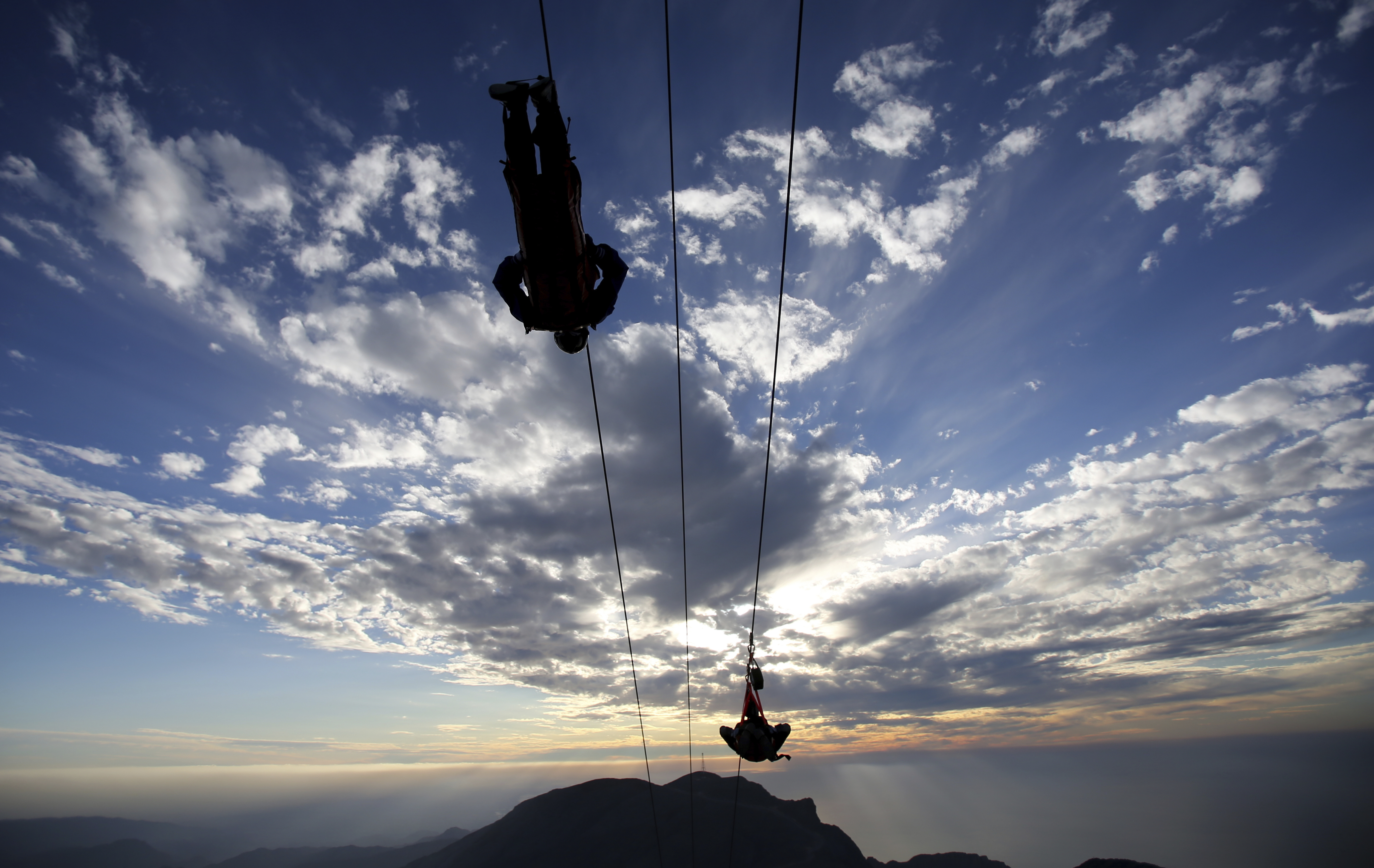 In this Wednesday, Jan. 31, 2018 photo, thrill-seekers descind the UAE's highest mountain as they try out a new zip line, on the peak of Jebel Jais mountain, 25 kms (15.5 miles) north east of Ras al-Khaimah, United Arab Emirates. The UAE is claiming a new world record with the opening of the world's longest zip line, measuring 2.83 kilometers (1.76 miles) in length. Guinness World Records officials certified the zip line on Thursday, the same day the attraction opened to the public. (AP Photo/Kamran Jebreili)