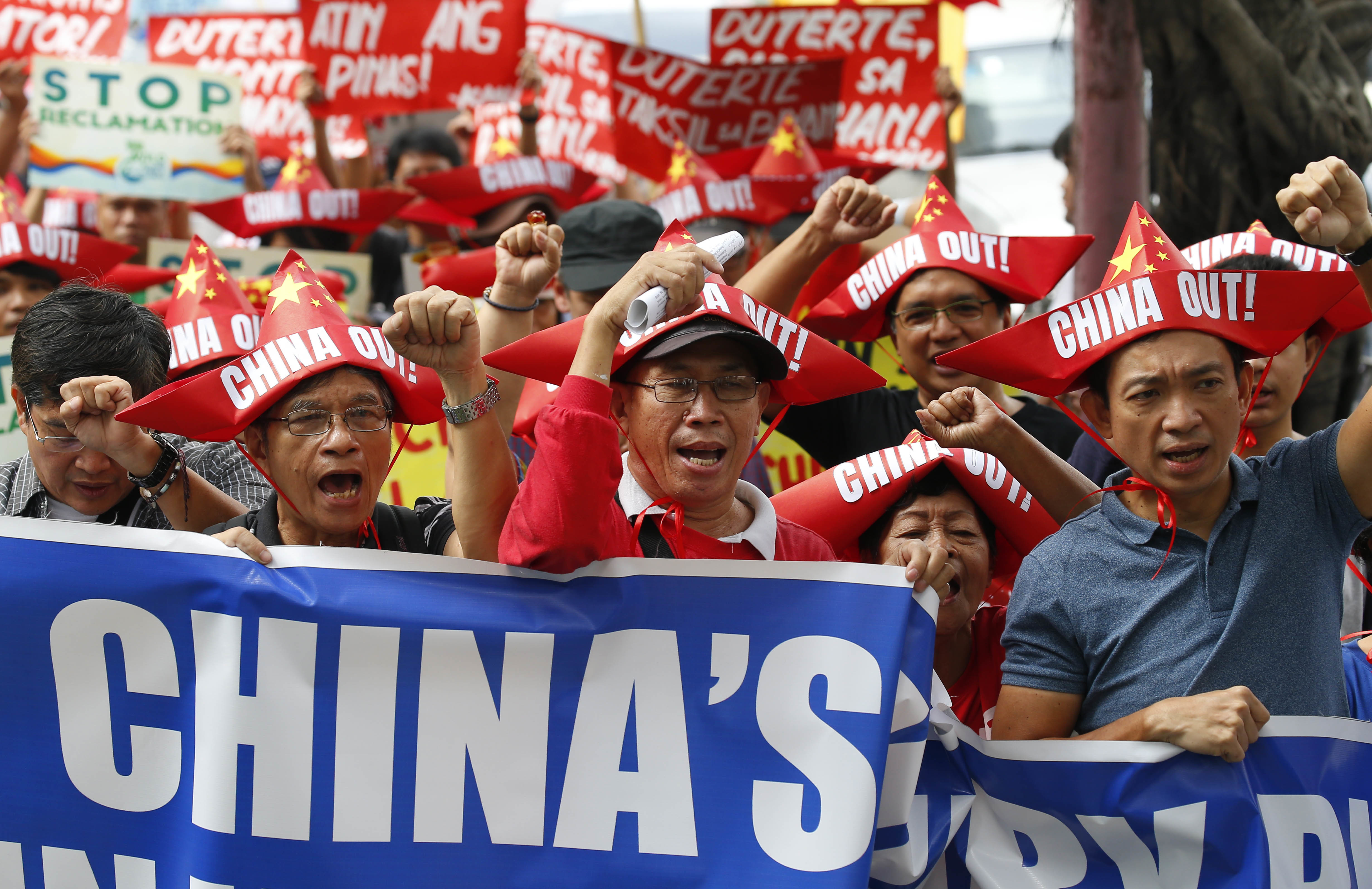 Protesters, wearing boat-shaped paper hats, shout slogans as they march for rally at the Chinese Consulate to protest China's alleged continued militarization of the disputed islands in the South China Sea known as Spratlys Saturday, Feb. 10, 2018 in the financial district of Makati city east of Manila, Philippines. The protesters also denounced President Rodrigo Duterte's inaction over China's continued build up of military facilities and structures at the disputed islands. (AP Photo/Bullit Marquez)