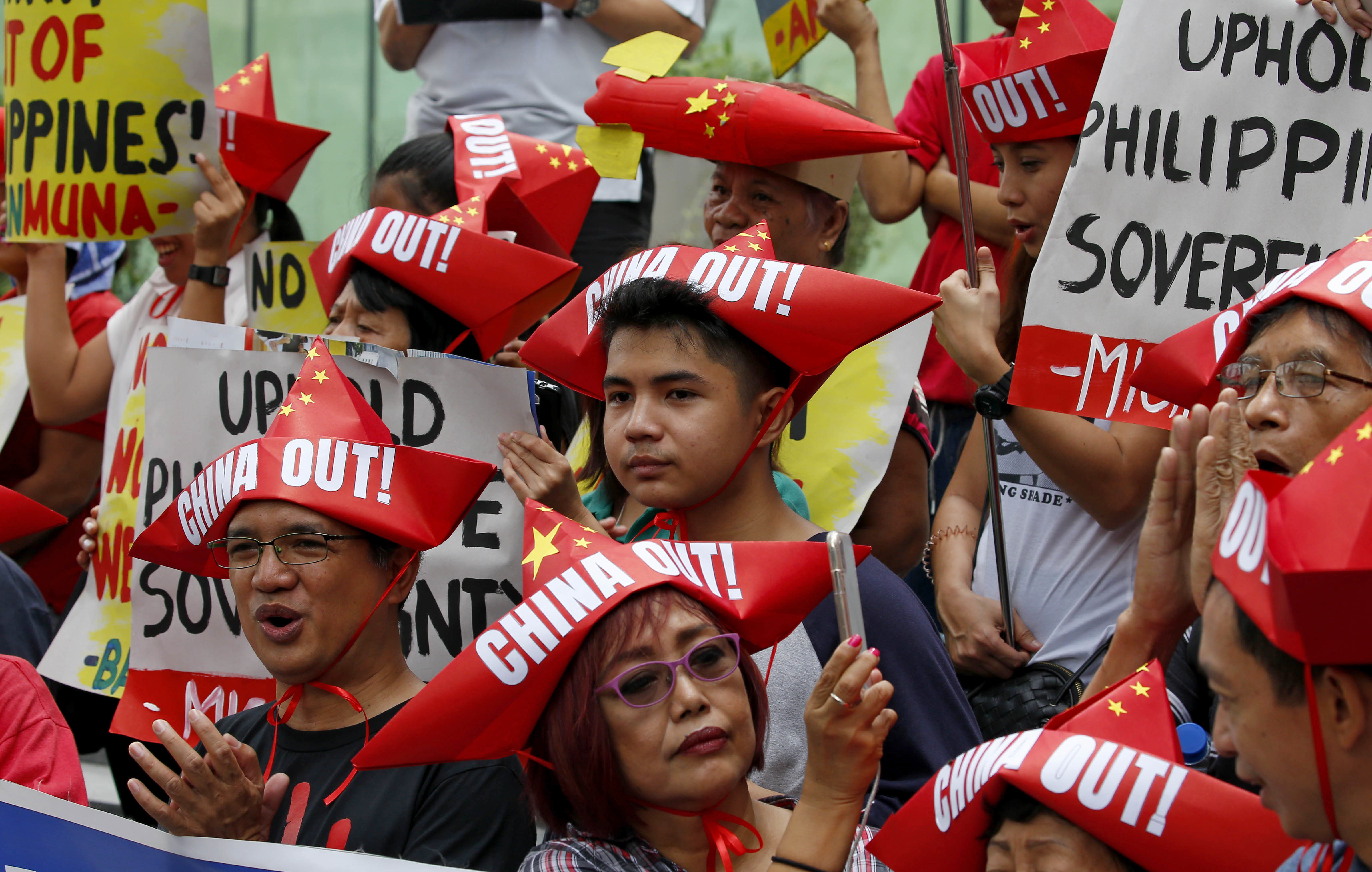 Protesters, wearing boat-shaped paper hats, shout slogans during a rally at the Chinese Consulate to protest China's alleged continued militarization of the disputed islands in the South China Sea known as Spratlys Saturday, Feb. 10, 2018 in the financial district of Makati city east of Manila, Philippines. The protesters also denounced President Rodrigo Duterte's inaction over China's continued build up of military facilities and structures at the disputed islands. (AP Photo/Bullit Marquez)