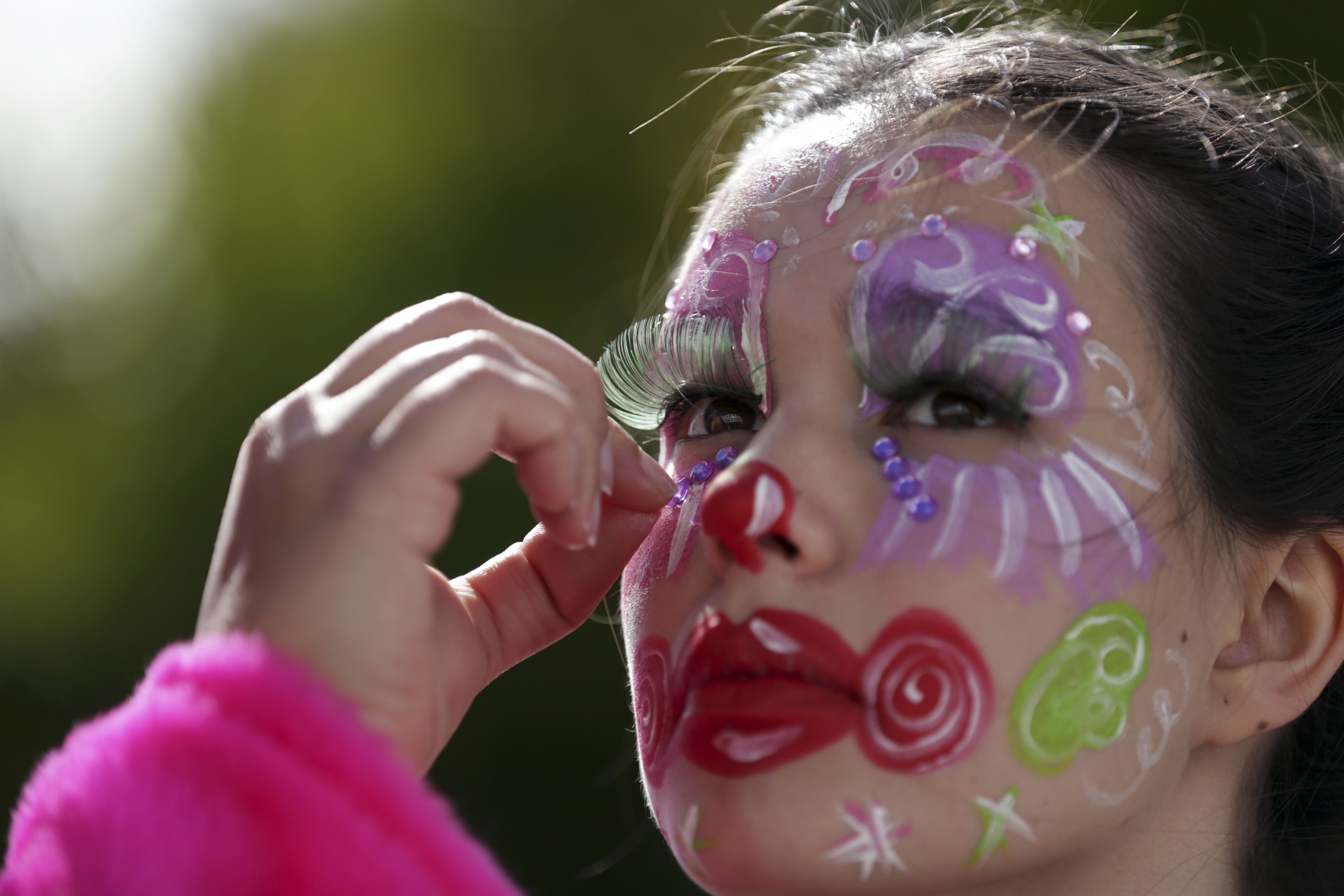 A girl gets makeup applied before taking part in the Carnival Clowns' Parade along the waterfront in Sesimbra, south of Lisbon, Monday, Feb. 12, 2018. Every year on Carnival Monday thousands dress as clowns to take part in the fishing town's parade. (AP Photo/Armando Franca)