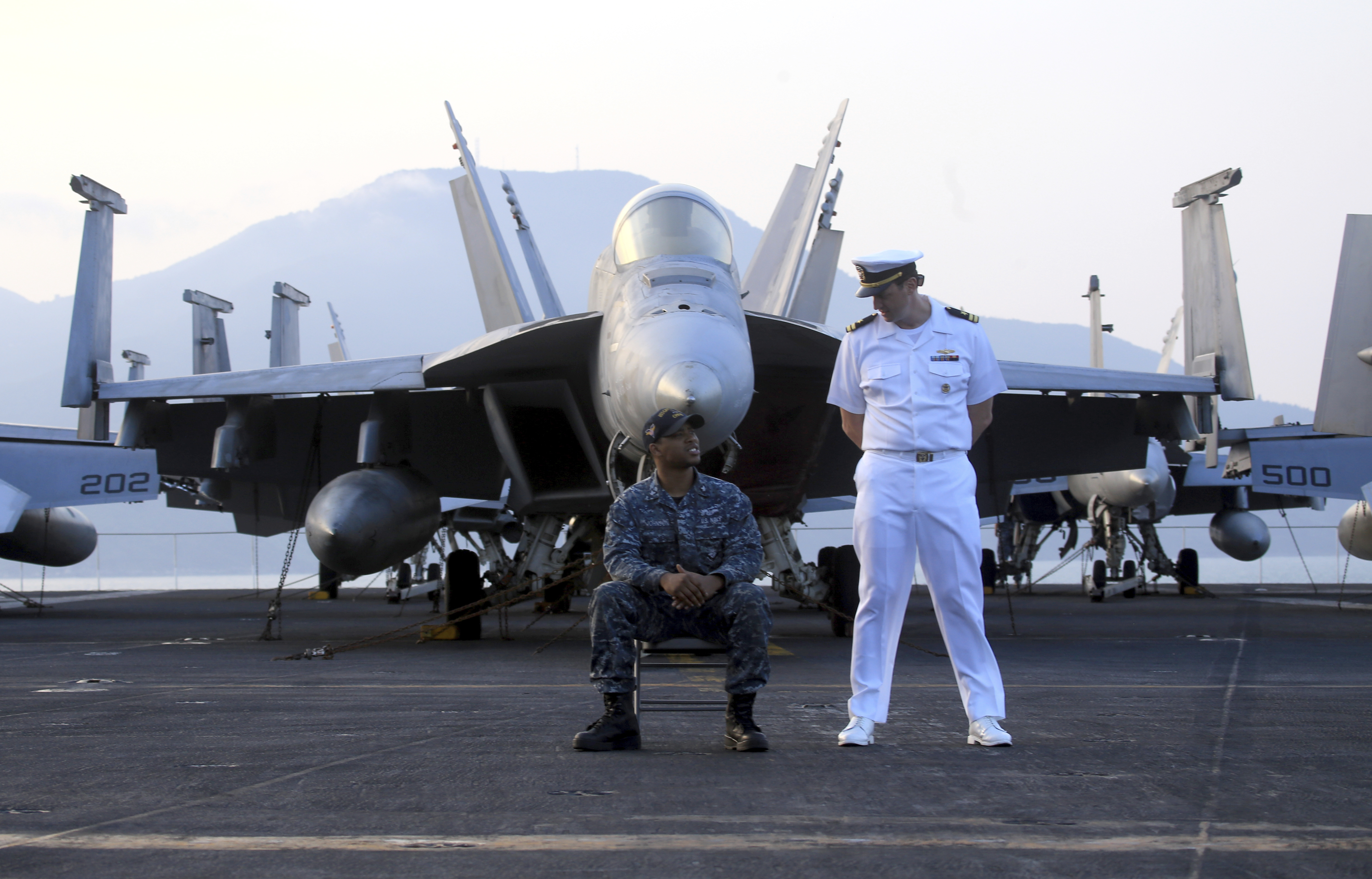 American navy officers talk to each other aboard the aircraft carrier USS Carl Vinson as it docks in Danang bay, Vietnam on Monday, March 5, 2018. For the first time since the Vietnam War, a U.S. Navy aircraft carrier is paying a visit to a Vietnamese port, seeking to bolster both countries' efforts to stem expansionism by China in the South China Sea. (AP Photo/ Hau Dinh)