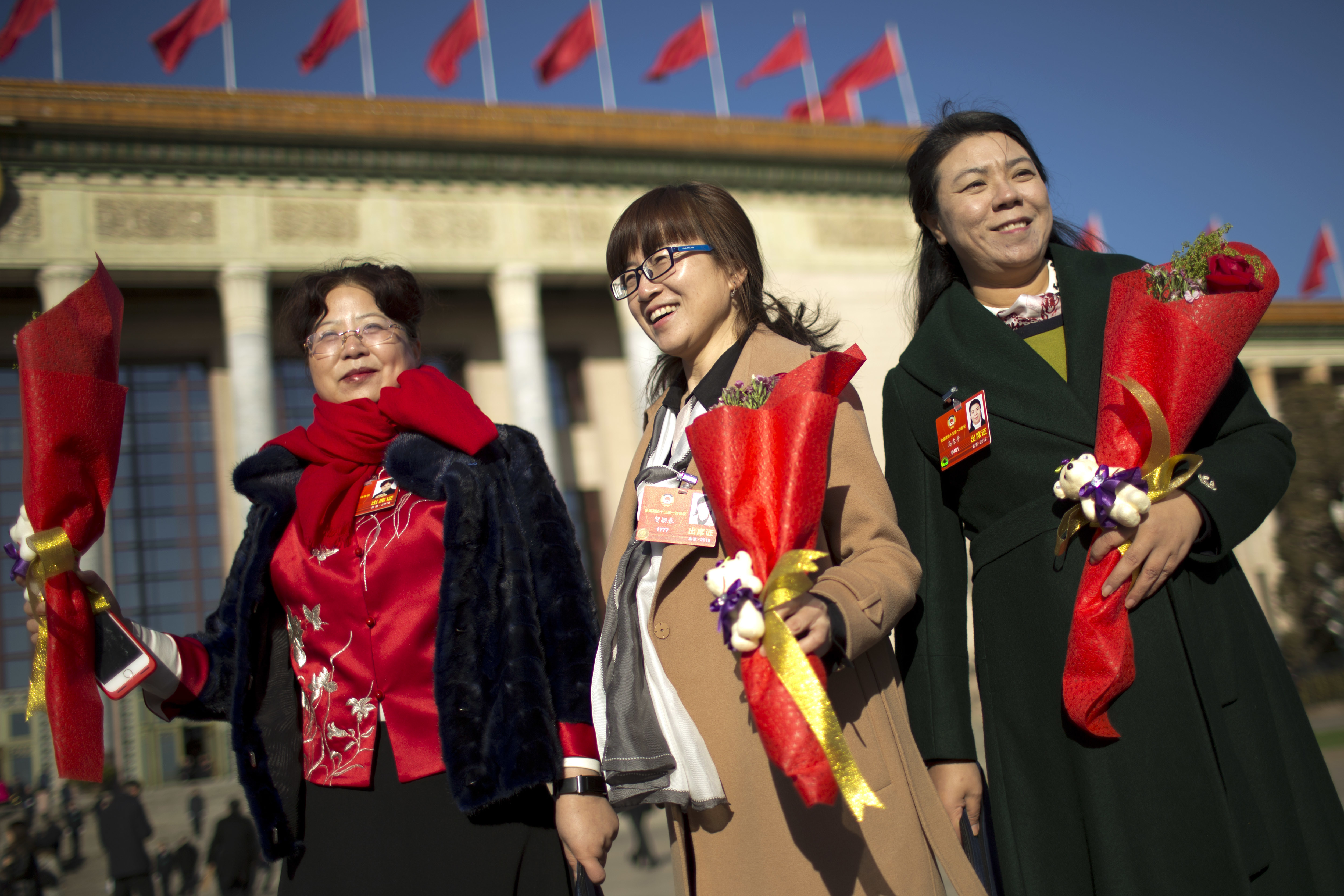Delegates hold flower bouquets for International Women's Day as they arrive for a plenary session of the Chinese People's Political Consultative Conference (CPPCC) at the Great Hall of the People in Beijing, Thursday, March 8, 2018. Students at China's prestigious Tsinghua University are celebrating International Women's Day with banners making light of a proposed constitutional amendment to scrap term limits for the country's president. (AP Photo/Mark Schiefelbein)
