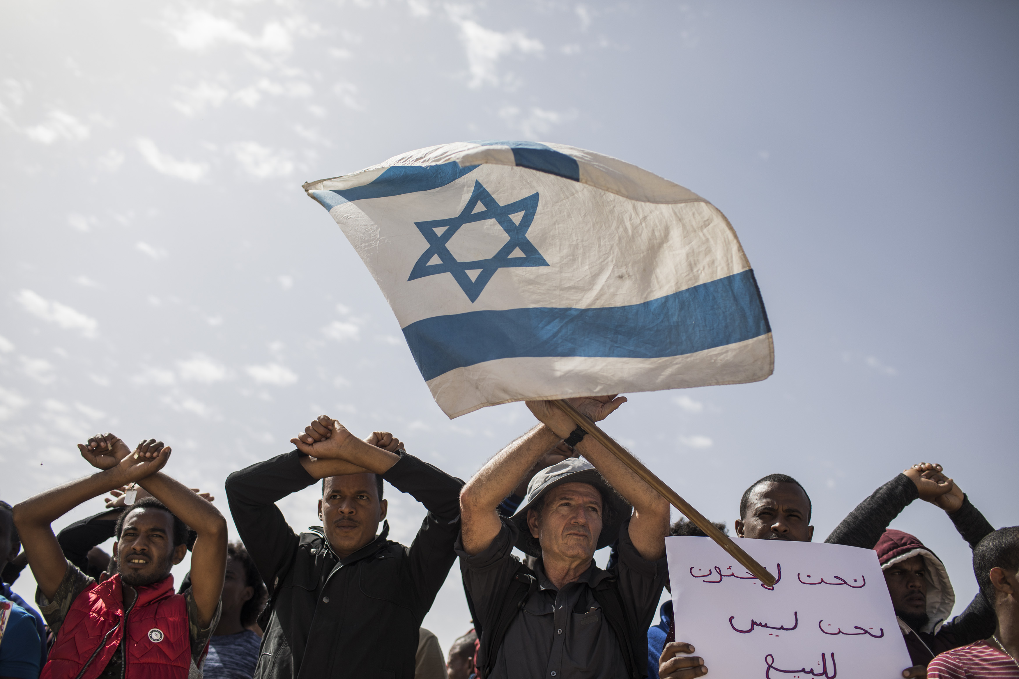 22.02.2018, Israel, Saharonim Gefängnis: Asybewerber und ihre Unterstützer schwenken eine israelische Fahne vor dem Gefängnis Saharonim in der Wüste Negev um gegen Regierungspläne zu protestieren, Afrikaner zwangsweise abzuschieben. Israel betrachtet die vor allem aus Eritrea und dem Sudan stammenden Flüchtlinge als illegale Einwanderer. Asylanträgen wird nur in extrem seltenen Fällen stattgegeben. Nach Medienberichten hat Israel eine Vereinbarung mit Ruanda und Uganda getroffen, dafür gibt es aber keine Bestätigung. Photo by: ilia yefimovich/picture-alliance/dpa/AP Images
