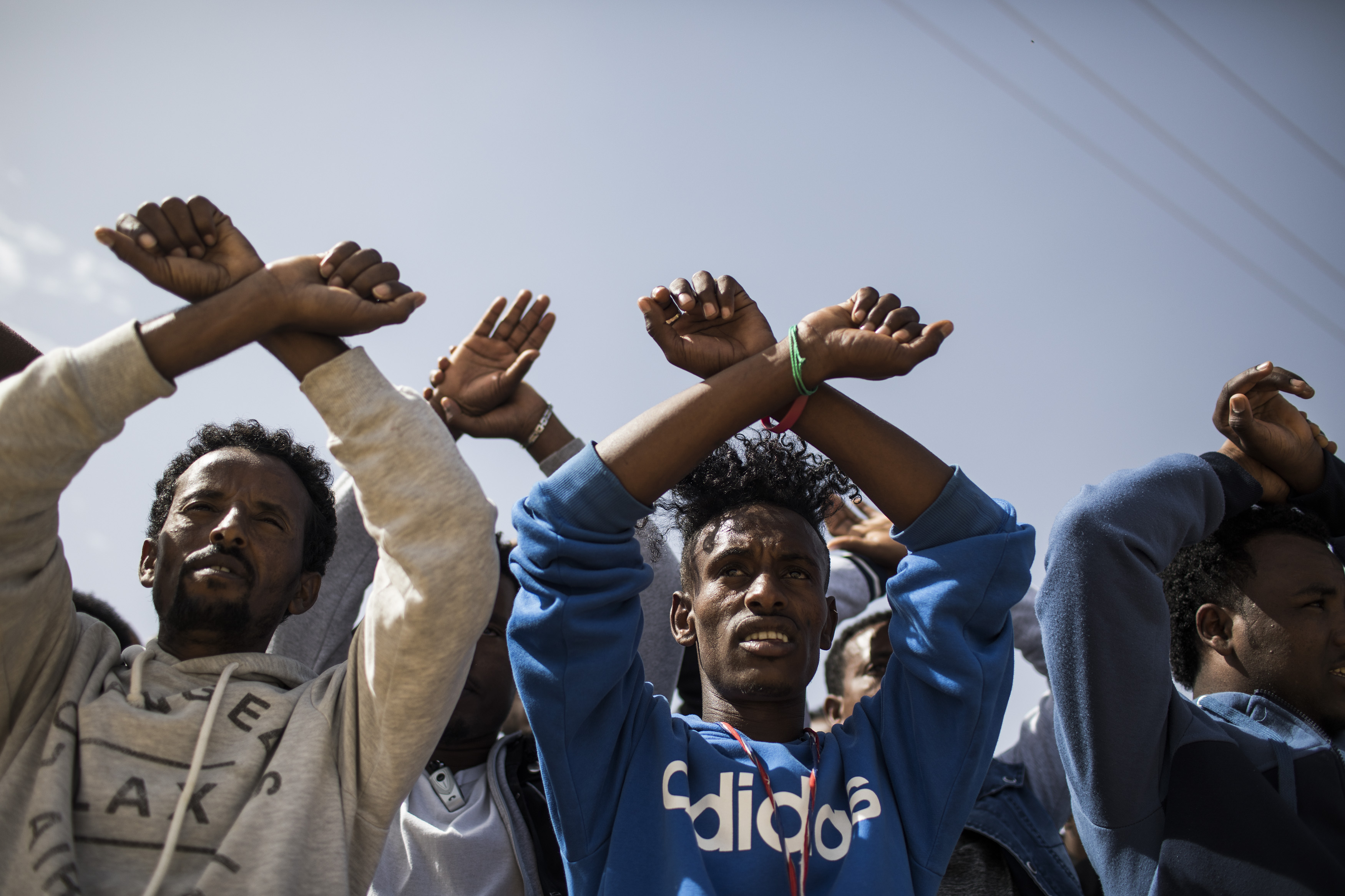 22.02.2018, Israel, Saharonim Gefängnis:  Asybewerber aus Eritrea halten ihre Hände wie in Handschellen vor dem Gefängnis Saharonim in der Wüste Negev um gegen Regierungspläne zu protestieren, Afrikaner zwangsweise abzuschieben. Israel betrachtet die vor allem aus Eritrea und dem Sudan stammenden Flüchtlinge als illegale Einwanderer. Asylanträgen wird nur in extrem seltenen Fällen stattgegeben. Nach Medienberichten hat Israel eine Vereinbarung mit Ruanda und Uganda getroffen, dafür gibt es aber keine Bestätigung. Photo by: ilia yefimovich/picture-alliance/dpa/AP Images