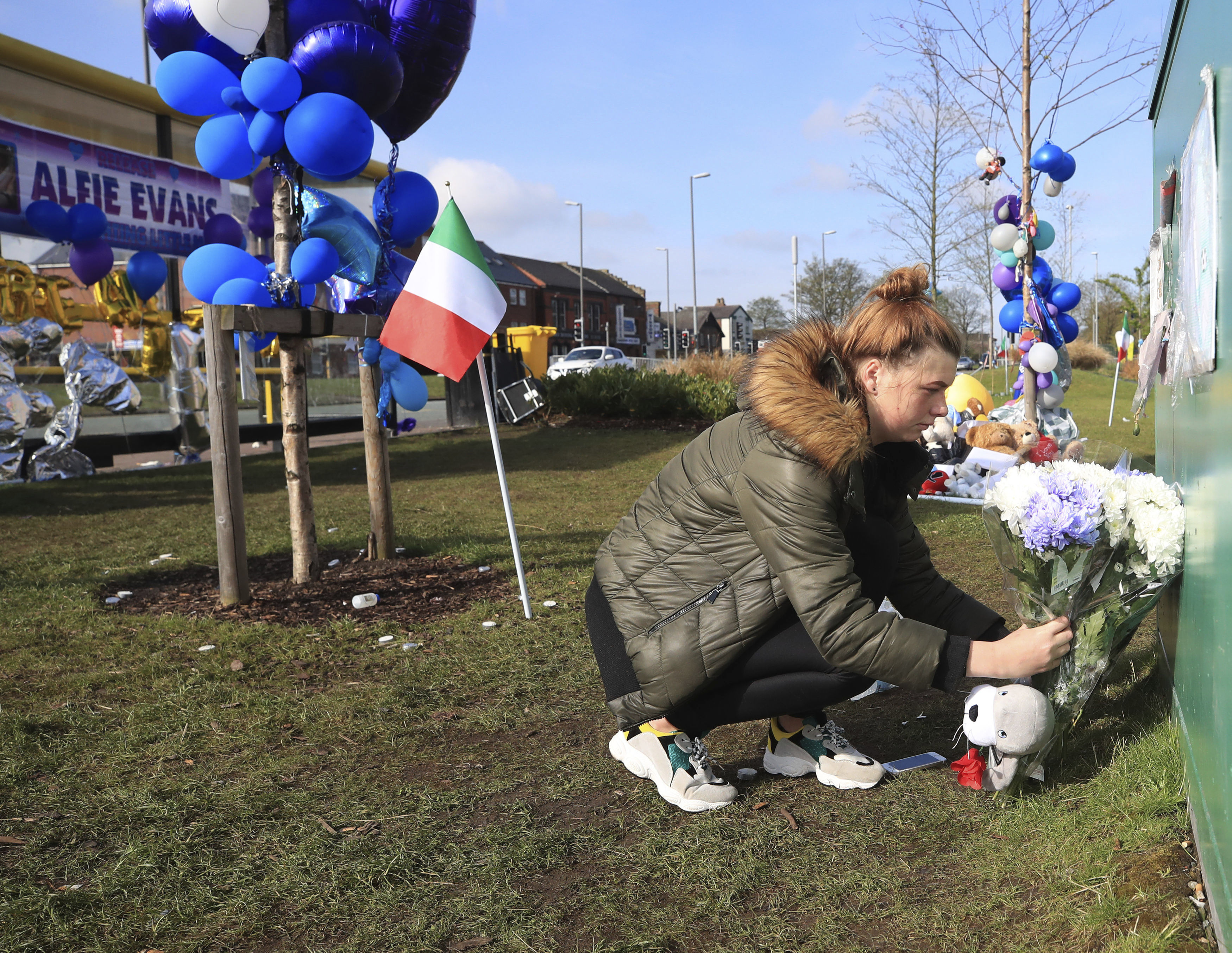 A woman leaves flowers outside Alder Hey Children's Hospital in Liverpool, England, following the death of 23-month-old, Alfie Evans, Saturday April 28, 2018. Alfie Evans, the sick British toddler whose parents won support from Pope Francis during a protracted legal battle over his treatment, died early Saturday. He was 23 months old. (Peter Byrne/PA via AP)