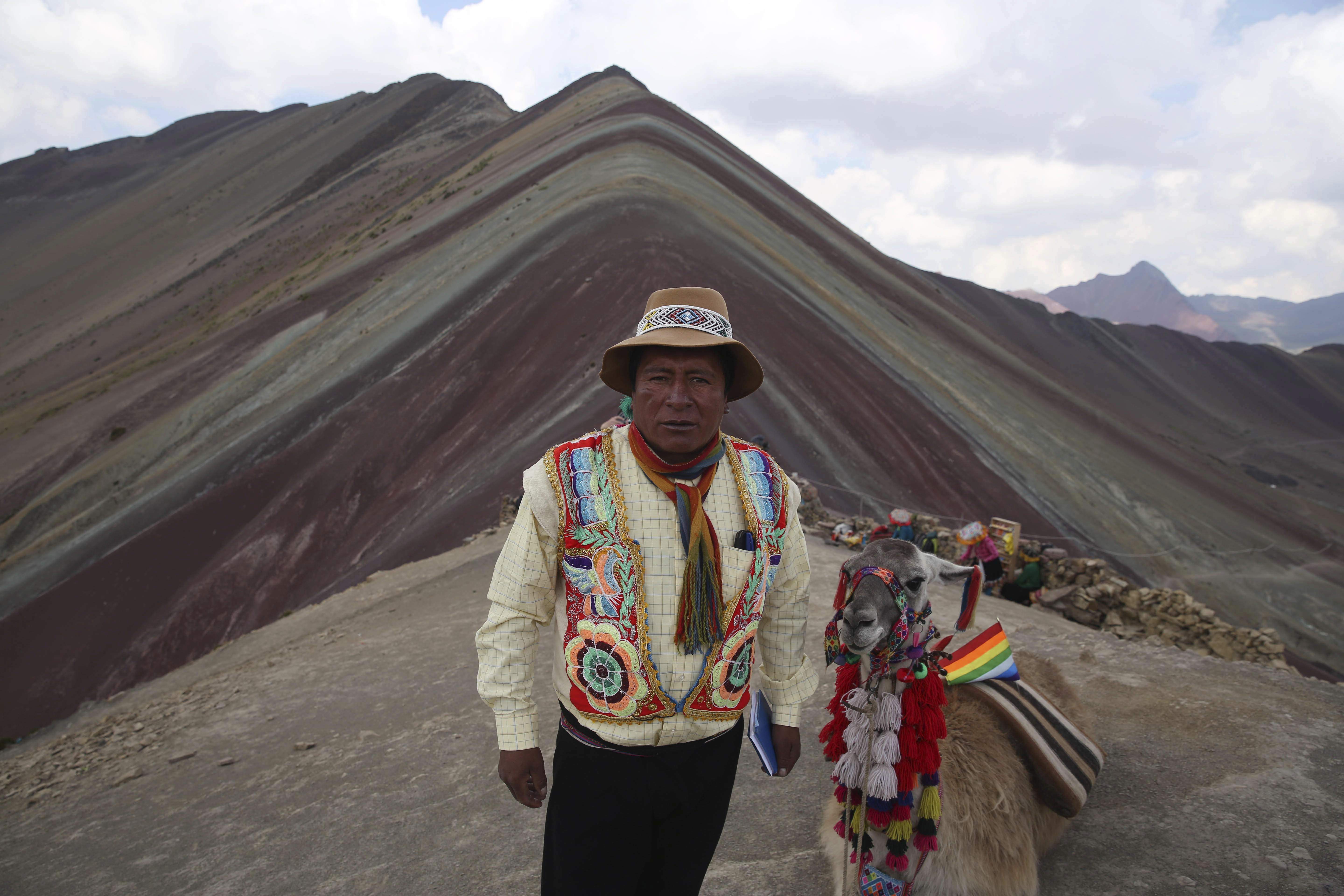 In this April 5, 2018 photo, community leader Gabino Human poses for a photo backdropped by Rainbow Mountain, in Pitumarca, Peru. A surge in tourists comes with a responsibility to be good stewards of the environment and their new guests, says Huaman, who admits he's not sure they are ready to fully handle it. (AP Photo/Martin Mejia)