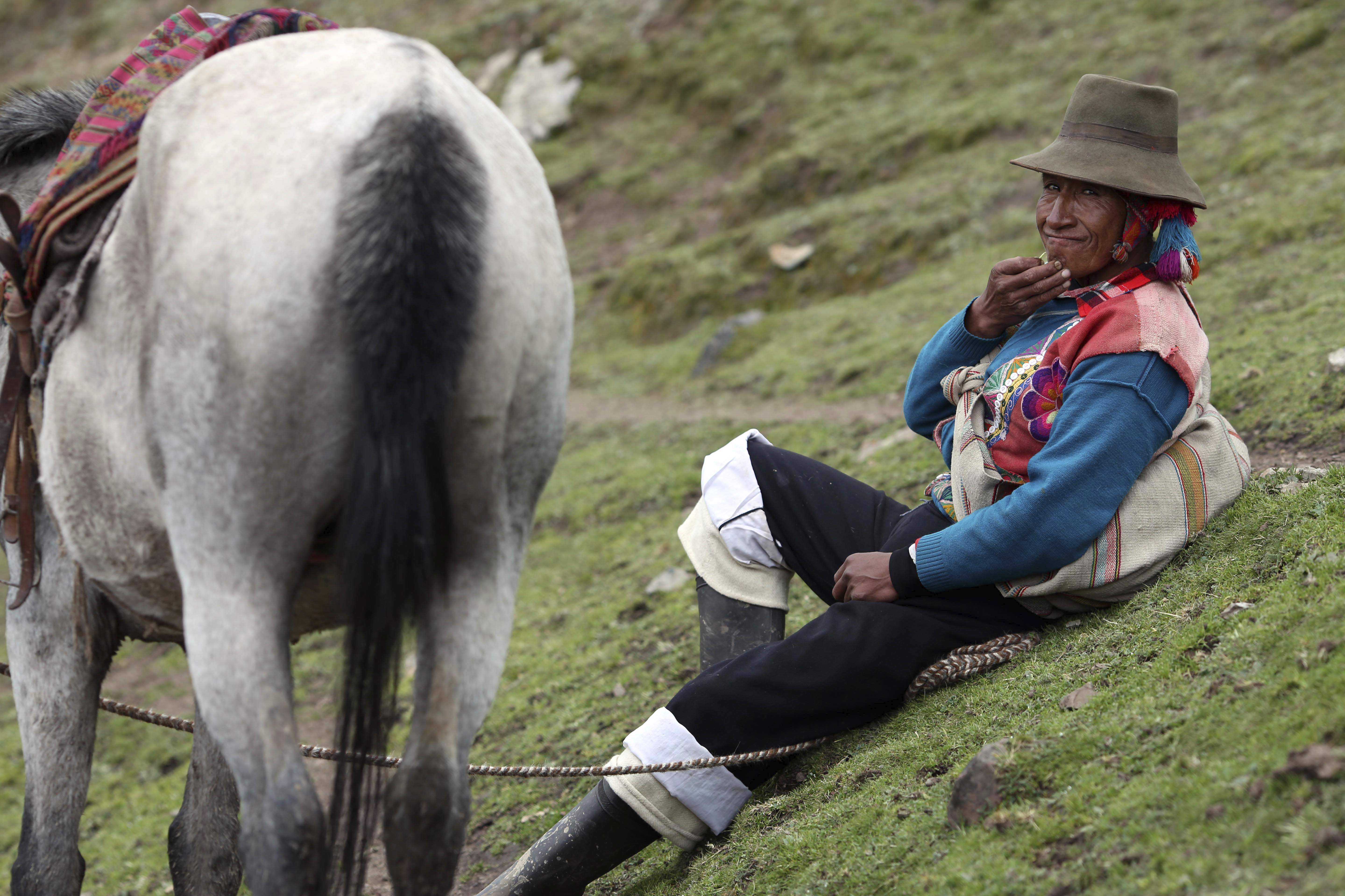 In this March 2, 2018 photo, an Andean muleteer rests during a break from guiding tourists to Rainbow Mountain, in Pitumarca, Peru. The 16,404-foot (5,000-meter) peak of multicolored sediments was laid down millions of years ago, then pushed up clashing tectonic plates, but it's only within the last five years that the wonder has been discovered by outsiders. (AP Photo/Martin Mejia)