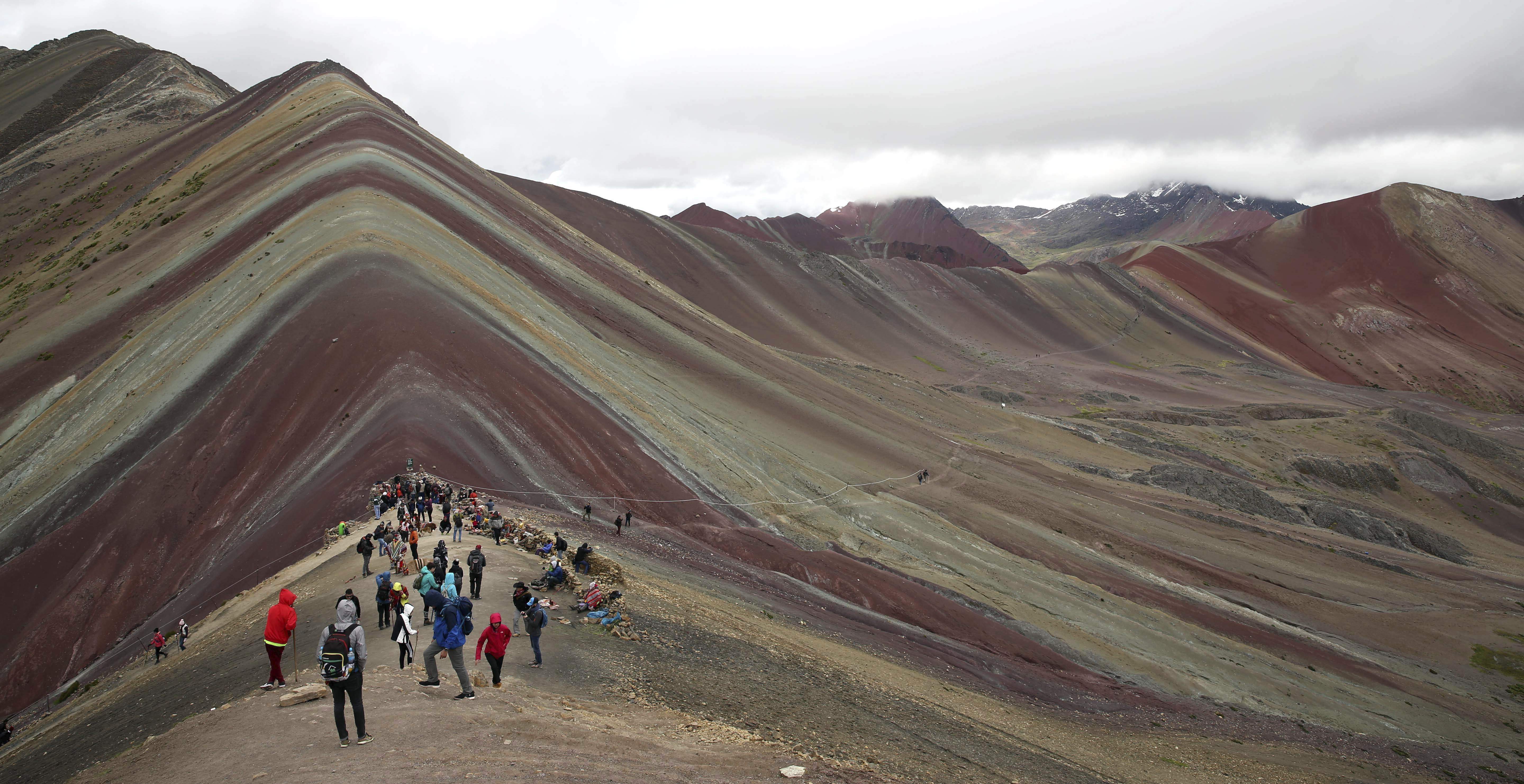 In this March 2, 2018 photo, national and foreign tourists take in the natural wonder dubbed rainbow Mountain, in Pitumarca, Peru. (AP Photo/Martin Mejia)