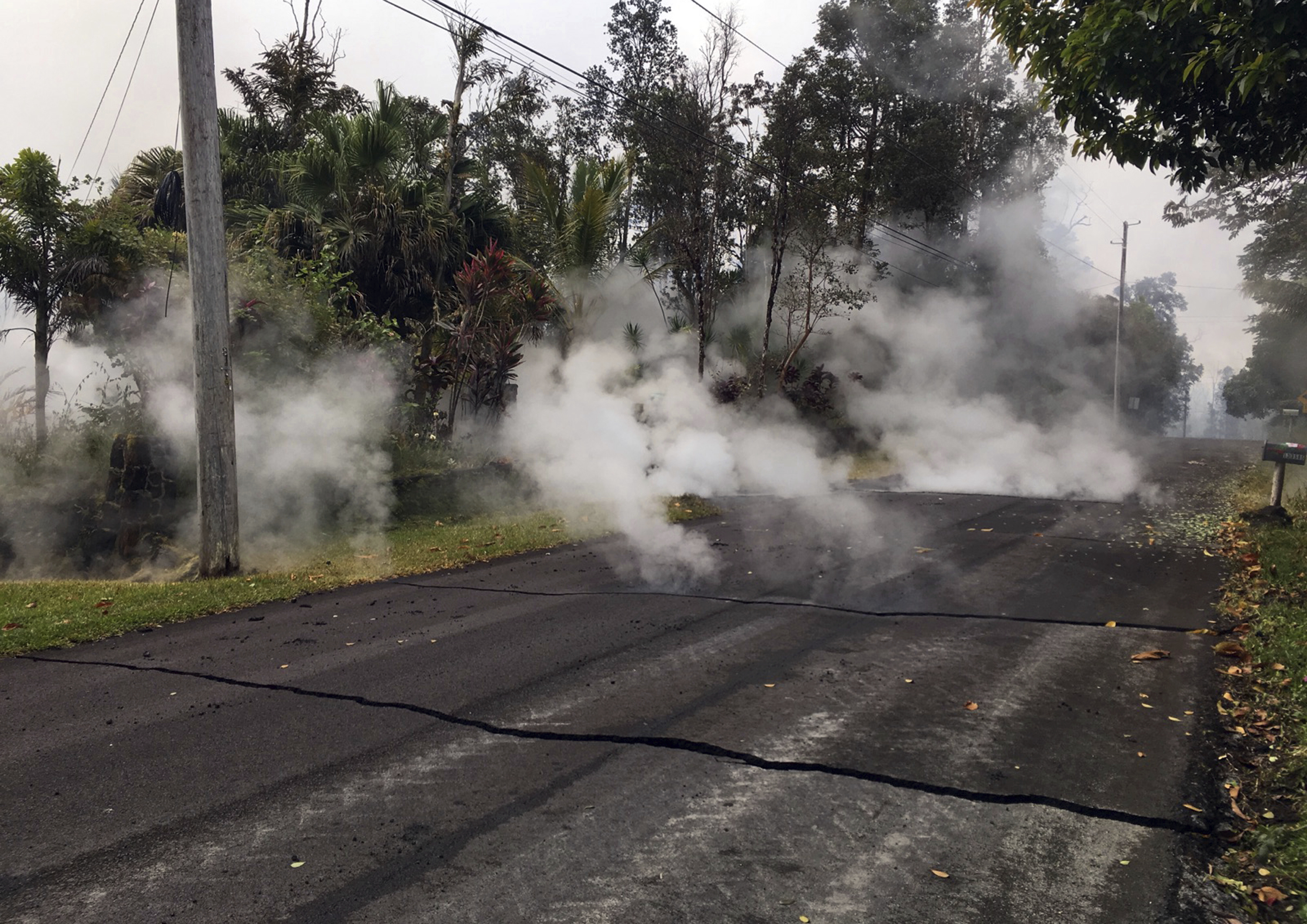 This Monday, May 7, 2018 photo from the U.S. Geological Survey shows gas and steam rising from multiple fissures on Moku Street in the Leilani Estates Subdivision near Pahoa on the island of Hawaii. Kilauea volcano has destroyed more than two dozen homes since it began spewing lava hundreds of feet into the air last week, and residents who evacuated don't know how long they might be displaced. The decimated homes were in the Leilani Estates subdivision, where molten rock, toxic gas and steam have been bursting through openings in the ground created by the volcano. (U.S. Geological Survey via AP)