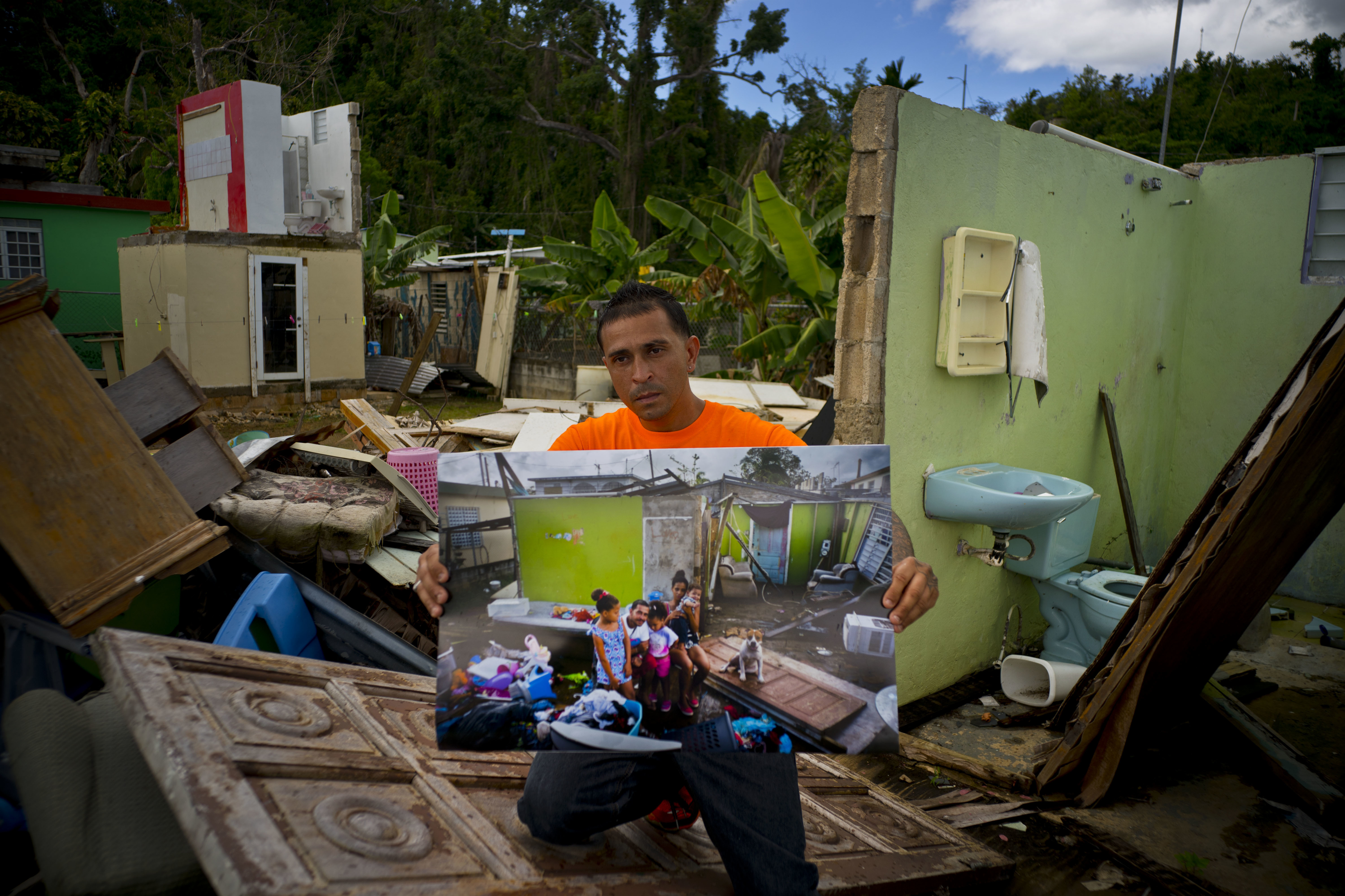 Arden Dragoni holds a printed photo taken on Oct. 5, 2017 that shows him with his wife Sindy, three children and dog Max, amid the remains of his home that was destroyed by Hurricane Maria, as he stands at the same spot where his home remains in shambles in Toa Baja, Puerto Rico, May 28, 2018. The unemployed construction worker and security guard is currently separated from his family while his wife and his children live in a FEMA subsidized apartment, and he lives with his father. 