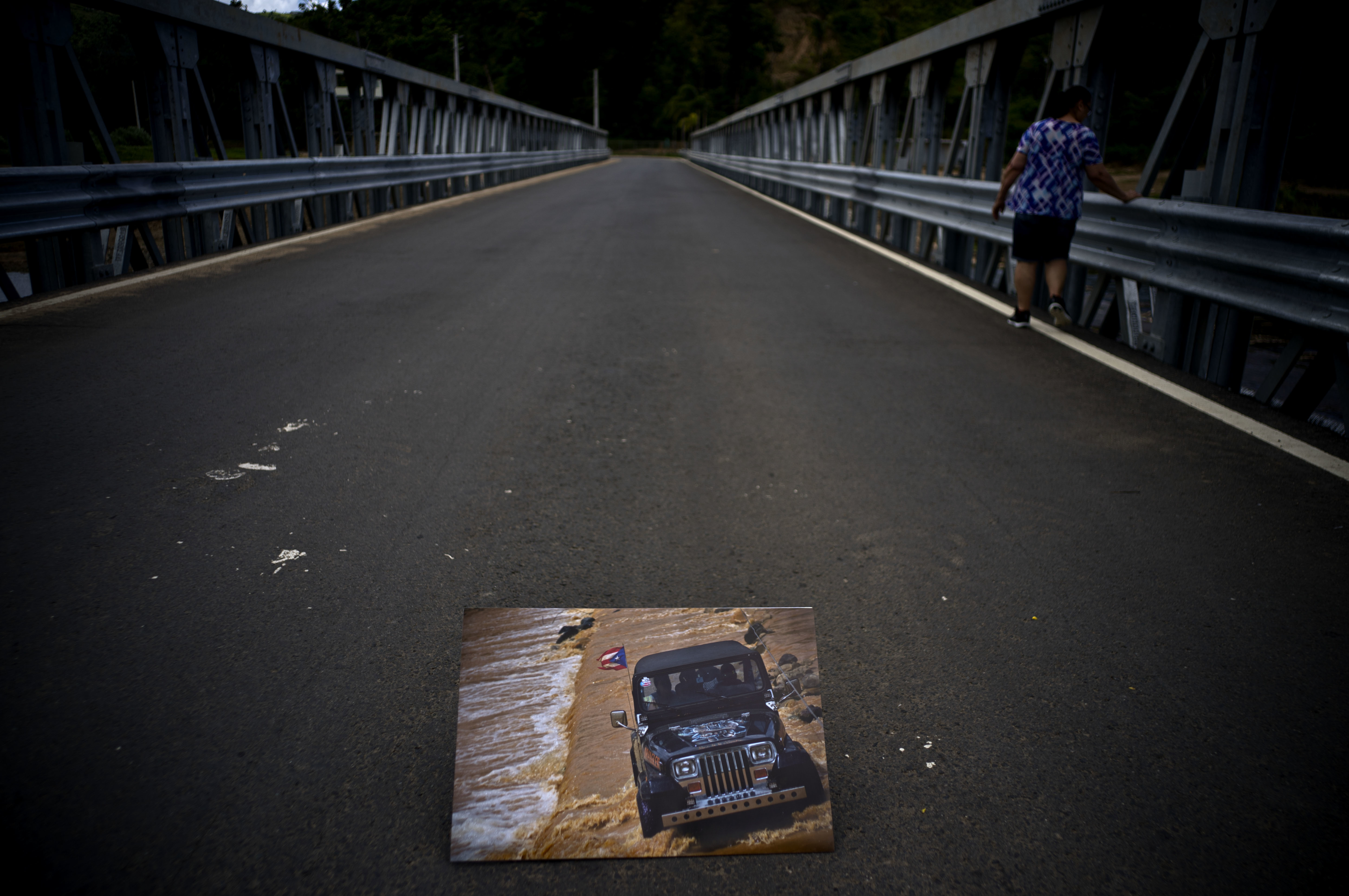 A printed photograph of a jeep crossing a river on Oct. 7, 2017 sits placed on a new bridge that stands above the spot where the print was taken after Hurricane Maria washed out the old bridge in the San Lorenzo neighborhood of Morovis, Puerto Rico, May 26, 2018. People on both sides of the bridge were left stranded when it collapsed, turning a 45 minute commute to the other side into a three hour oddesy. (AP Photo/Ramon Espinosa)