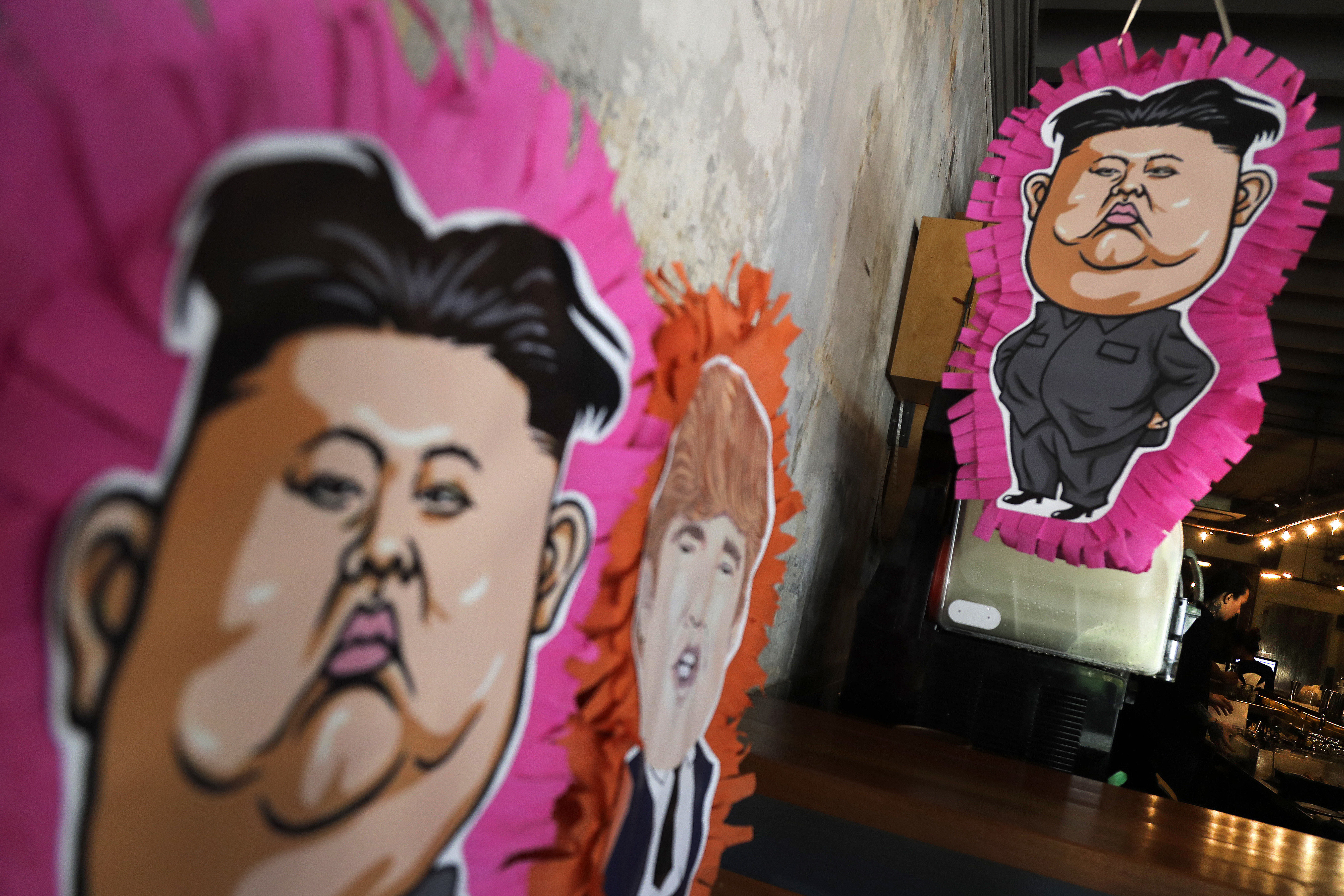 FILE - In this June 7, 2018, file photo, pinatas with the caricatures of U.S. President Donald Trump and North Korean leader Kim Jong Un decorate the Lucha Loco restaurant ahead of the their upcoming summit in Singapore. Singapore is a city that takes great pride in its food, so it’s not surprising that enterprising restaurateurs are using next week’s historic summit between U.S. President Donald Trump and North Korean leader Kim Jong Un to showcase some culinary creativity. Restaurants are marking the city-state’s time in the global spotlight with everything from red, white and blue cocktails to tacos named after the two leaders.(AP Photo/Wong Maye-E, File)