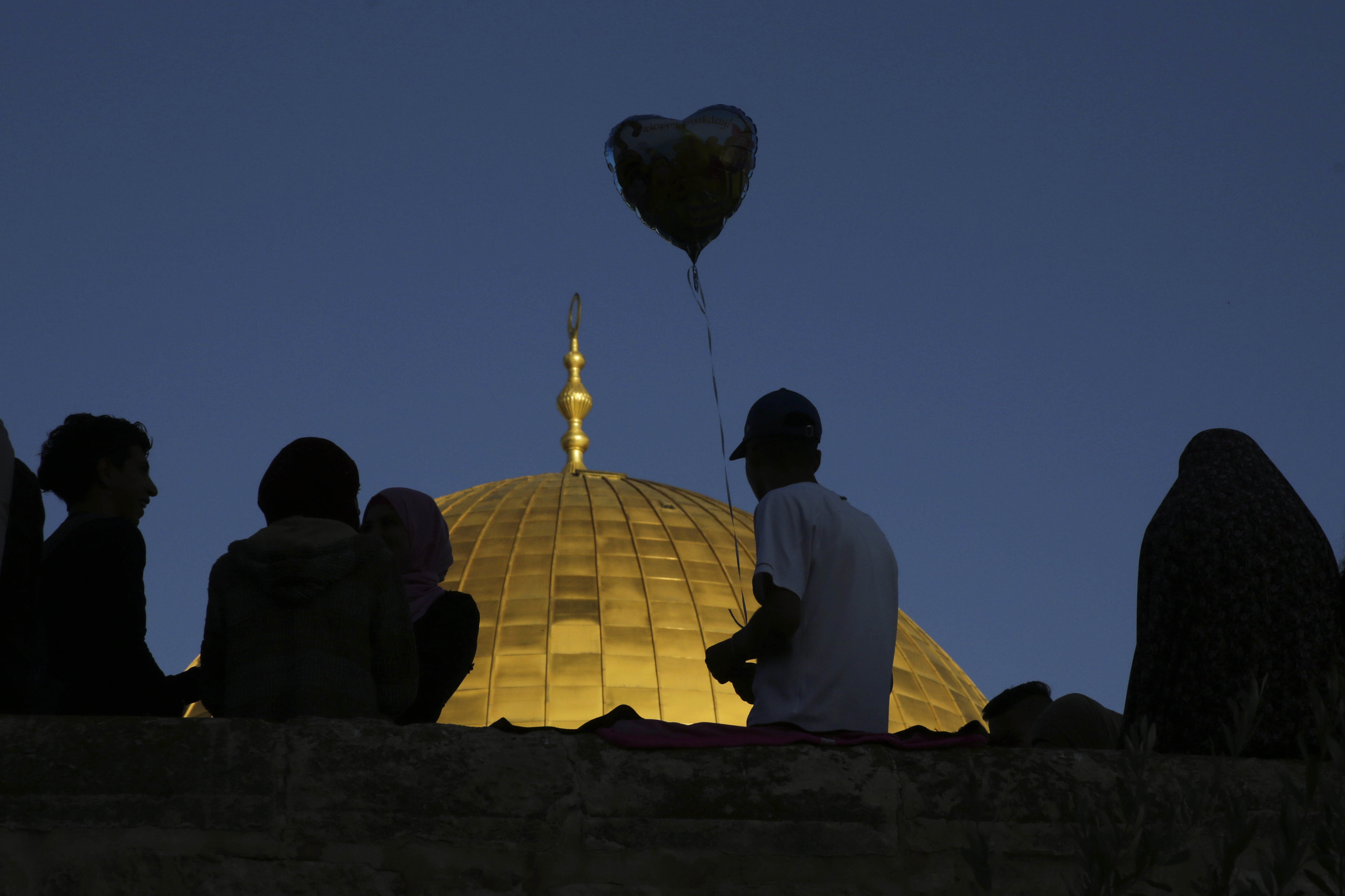 A Palestinian boy hold a balloon in front of the Dome of the Rock shrine in Jerusalem, Friday, June 15, 2018 during the traditional morning prayer of the Muslim holiday of Eid al-Fitr. (AP Photo/Mahmoud Illean)
