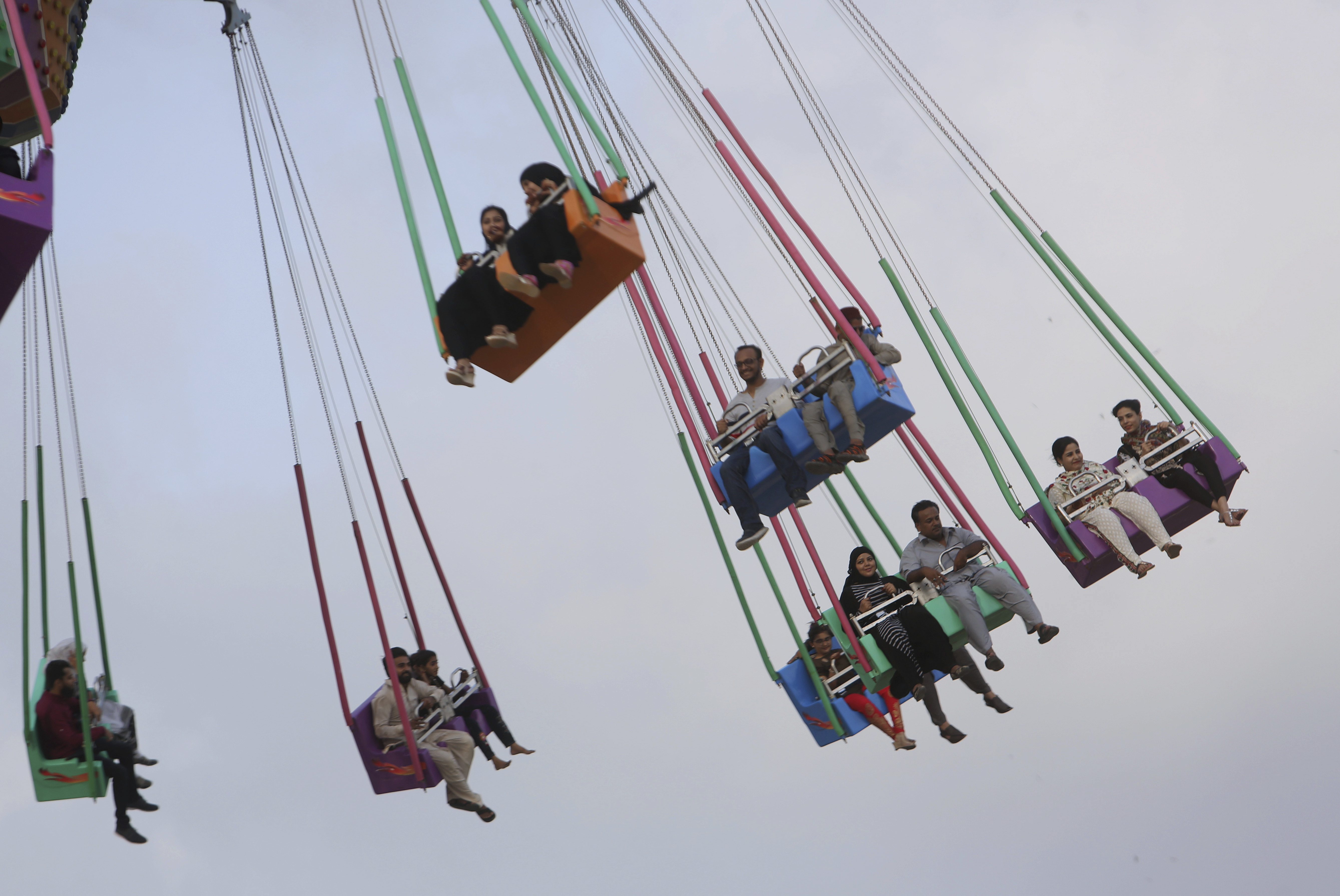 People enjoy a ride at a fair to celebrate the Eid al-Fitr holidays in Karachi, Pakistan, Saturday, June 16, 2018. Eid al-Fitr marks the end of the Islamic holy Islamic month of Ramadan, during which devout Muslims all over the world fast from sunrise to sunset. (AP Photo/Fareed Khan)