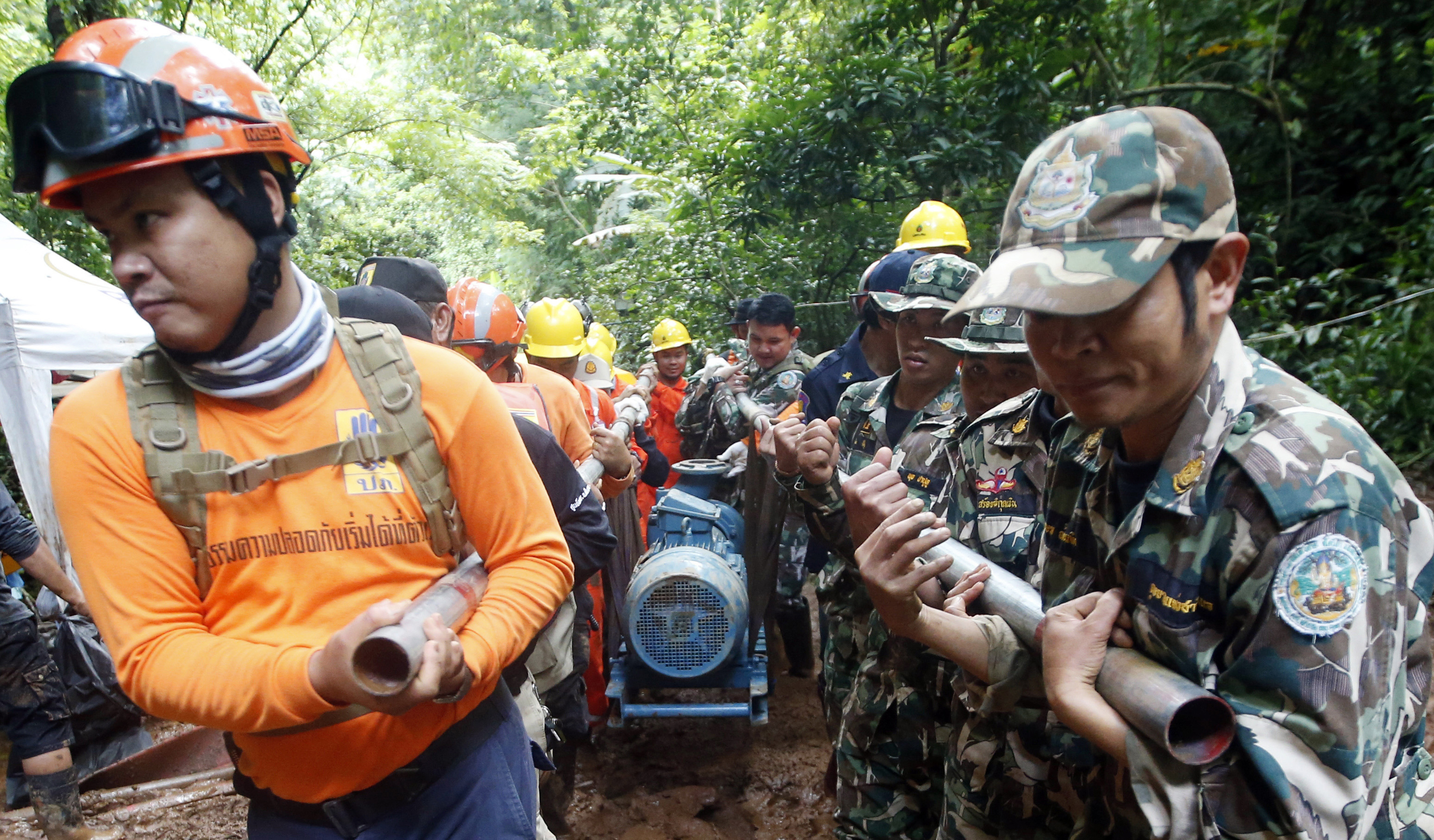Rescue personnel drag a water pump  up to the flooded cave that a soccer team and their coach are believed to be missing in, Thursday, June 28, 2018, in Mae Sai, Chiang Rai province, in northern Thailand. A U.S. military team and British cave experts have joined the rescue effort in northern Thailand for 12 boys and their soccer coach stranded for a fifth day inside a cave being flooded by near-constant rains. (AP Photo/Sakchai Lalit)