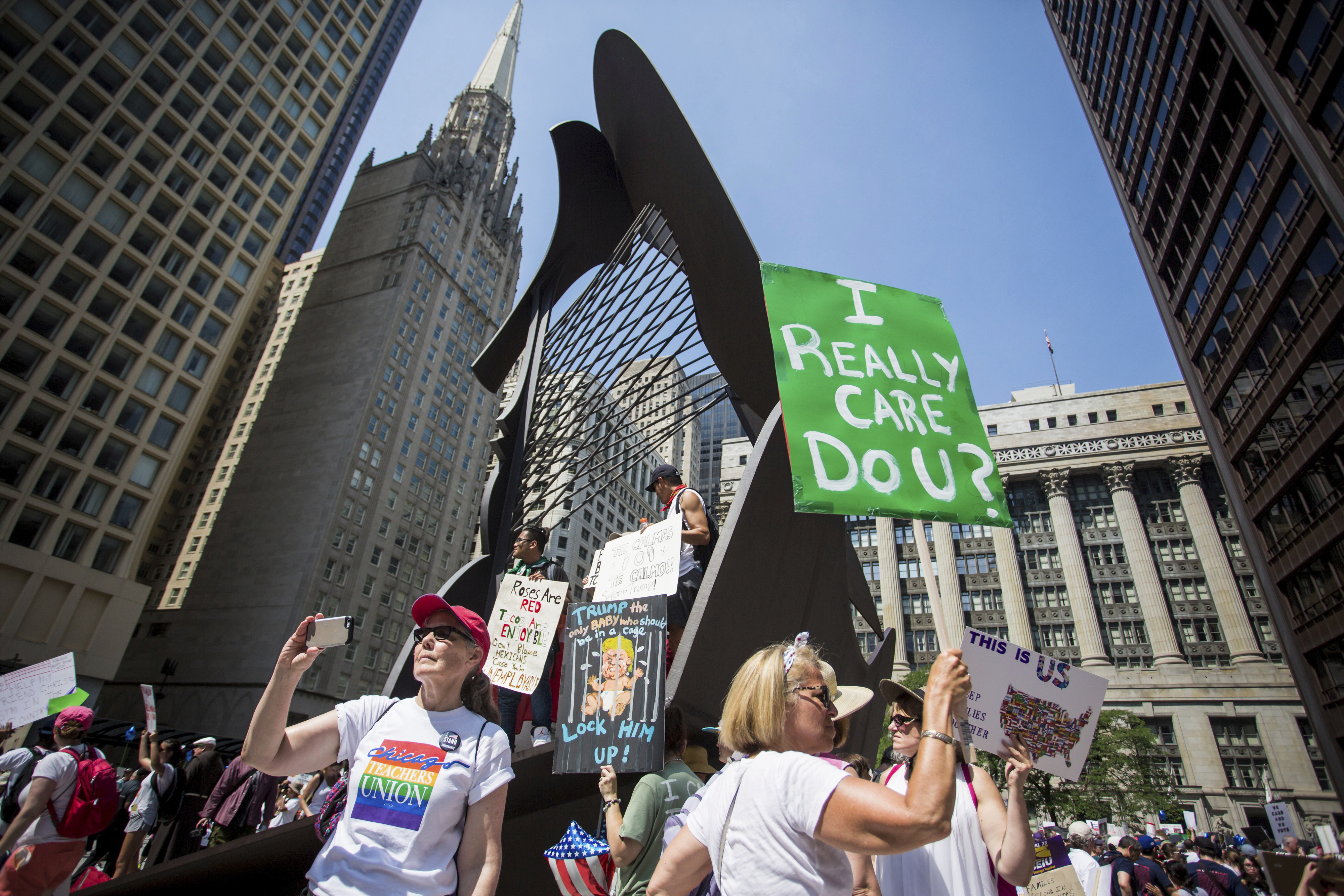 People hold signs as they participate in the Families Belong Together march in Chicago on Saturday, June 30, 2018. In major cities and tiny towns, marchers gathered across America, moved by accounts of children separated from their parents at the U.S.-Mexico border, in the latest act of mass resistance against President Donald Trump's immigration policies. (James Foster/Chicago Sun-Times via AP)