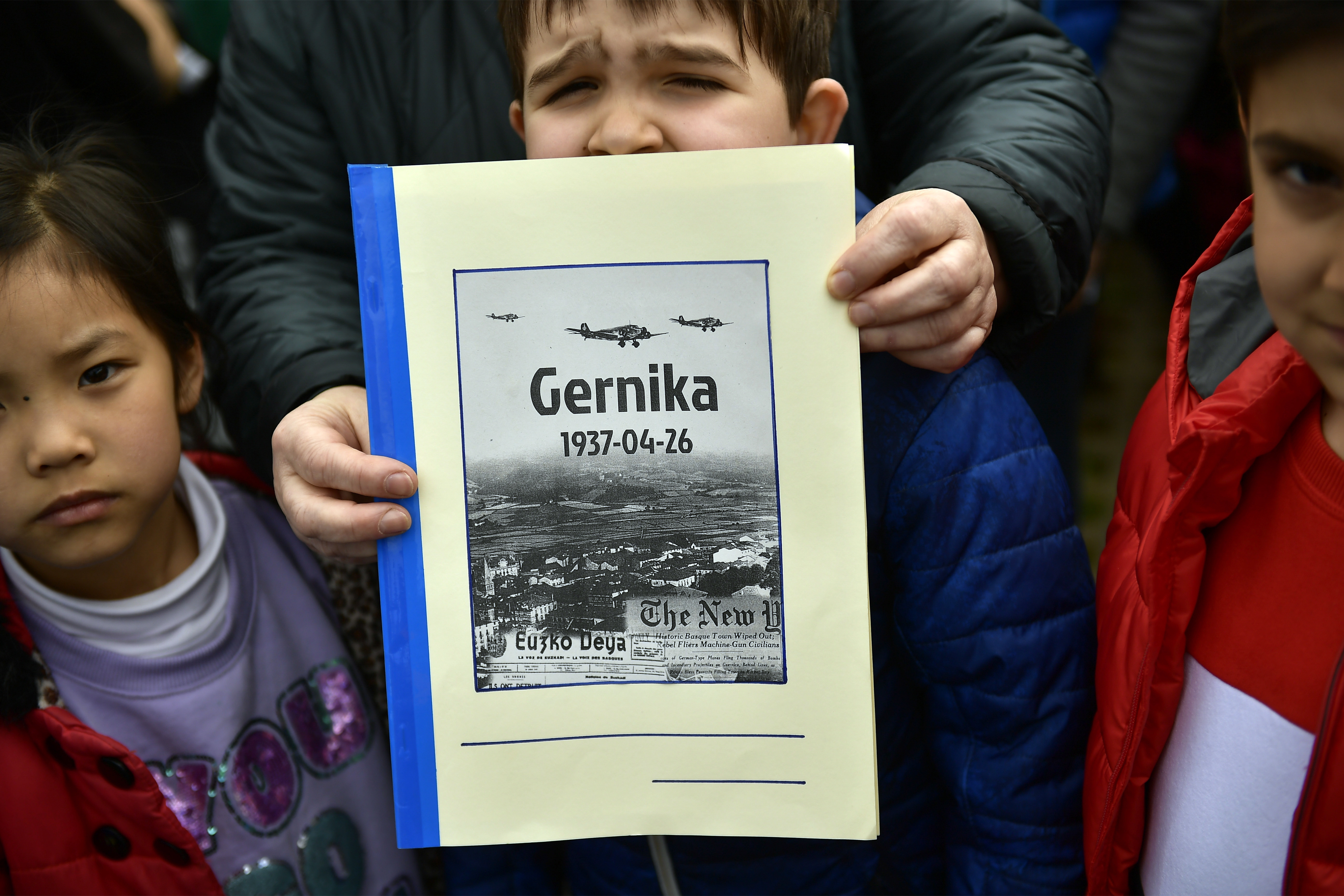 A young boy holds ups a magazine commemorating the 81st anniversary of Guernica and in tribute for all people killed in the Spanish Civil War, in Guernica, northern Spain, Thursday, April 26, 2018. The small town was destroyed in an attack by German bombers and thousands of Basque citizens died on this day in 1937. The carnage has ever since stood as a symbol of man's cruelty to his fellow man, immortalized in Pablo Picasso's immense and powerful painting, one of the most iconic works of art of the 20th century. (AP Photo/Alvaro Barrientos)